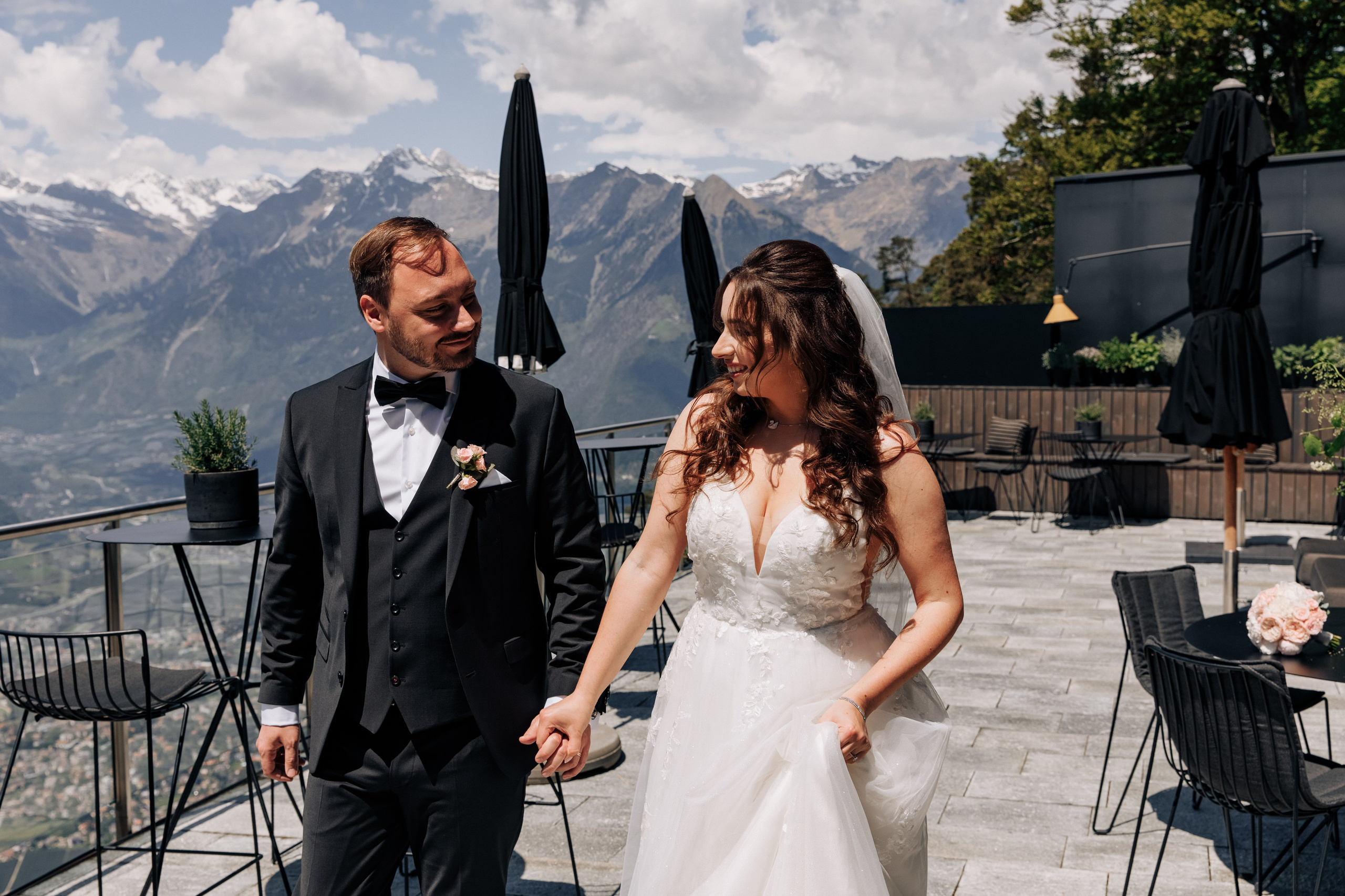 Der Bräutigam und die Braut schauen sich verliebt an und halten sich zärtlich an den Händen. 