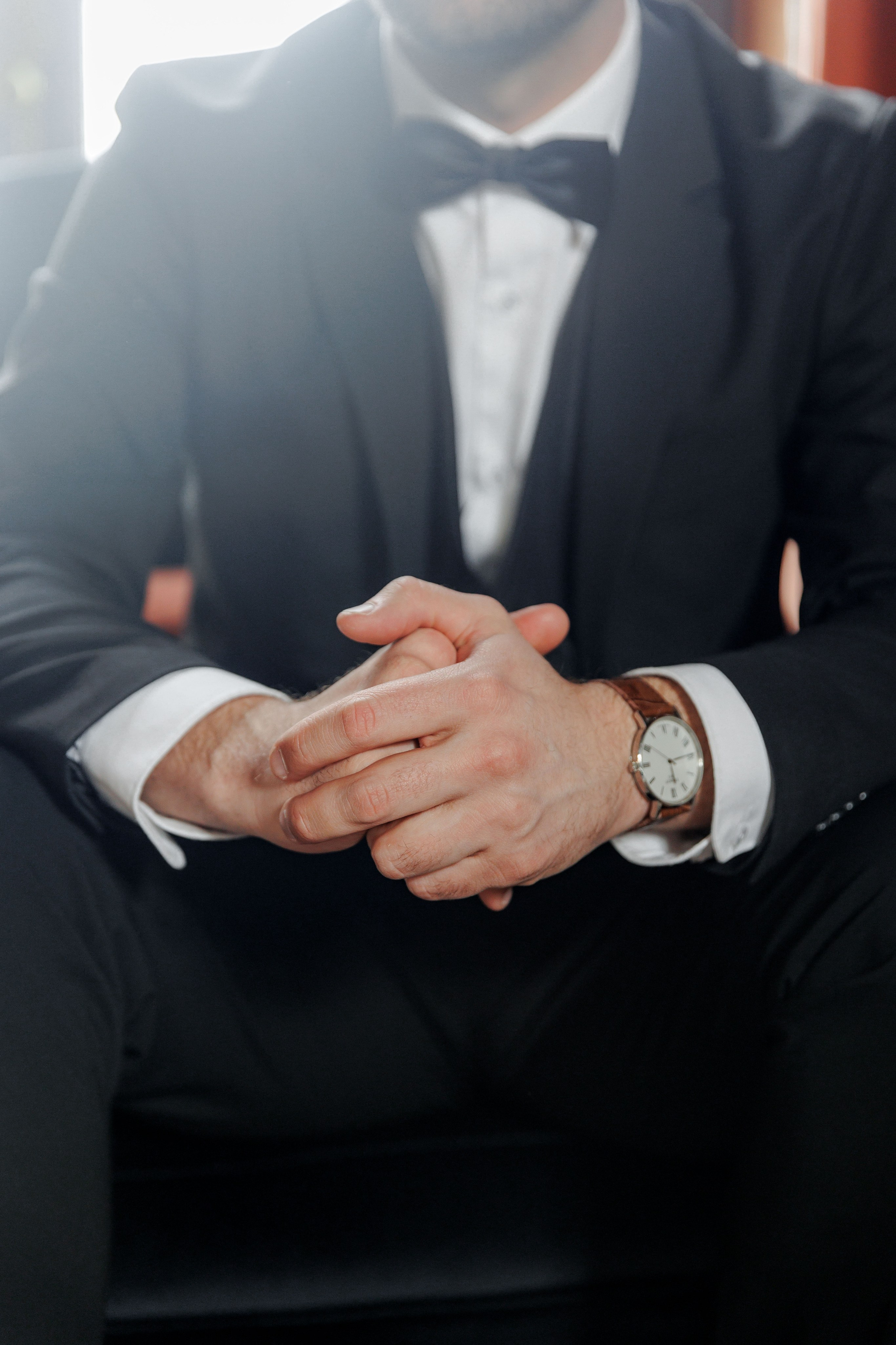 A stylish groom portrait captured in a picturesque French chateau setting showcases elegant wedding attire.