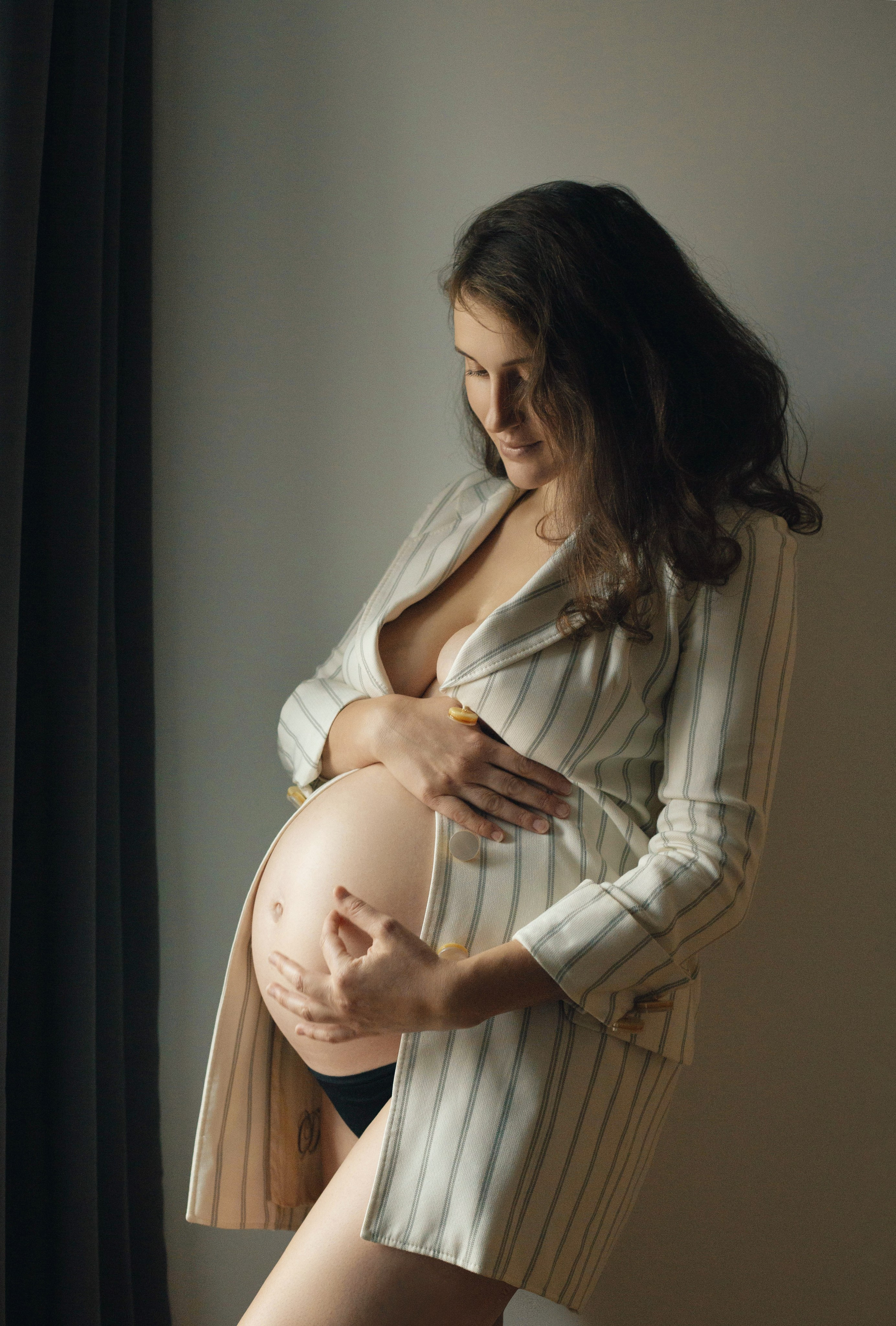 Séance photo maternité avec émotion, future maman regardant son ventre avec tendresse