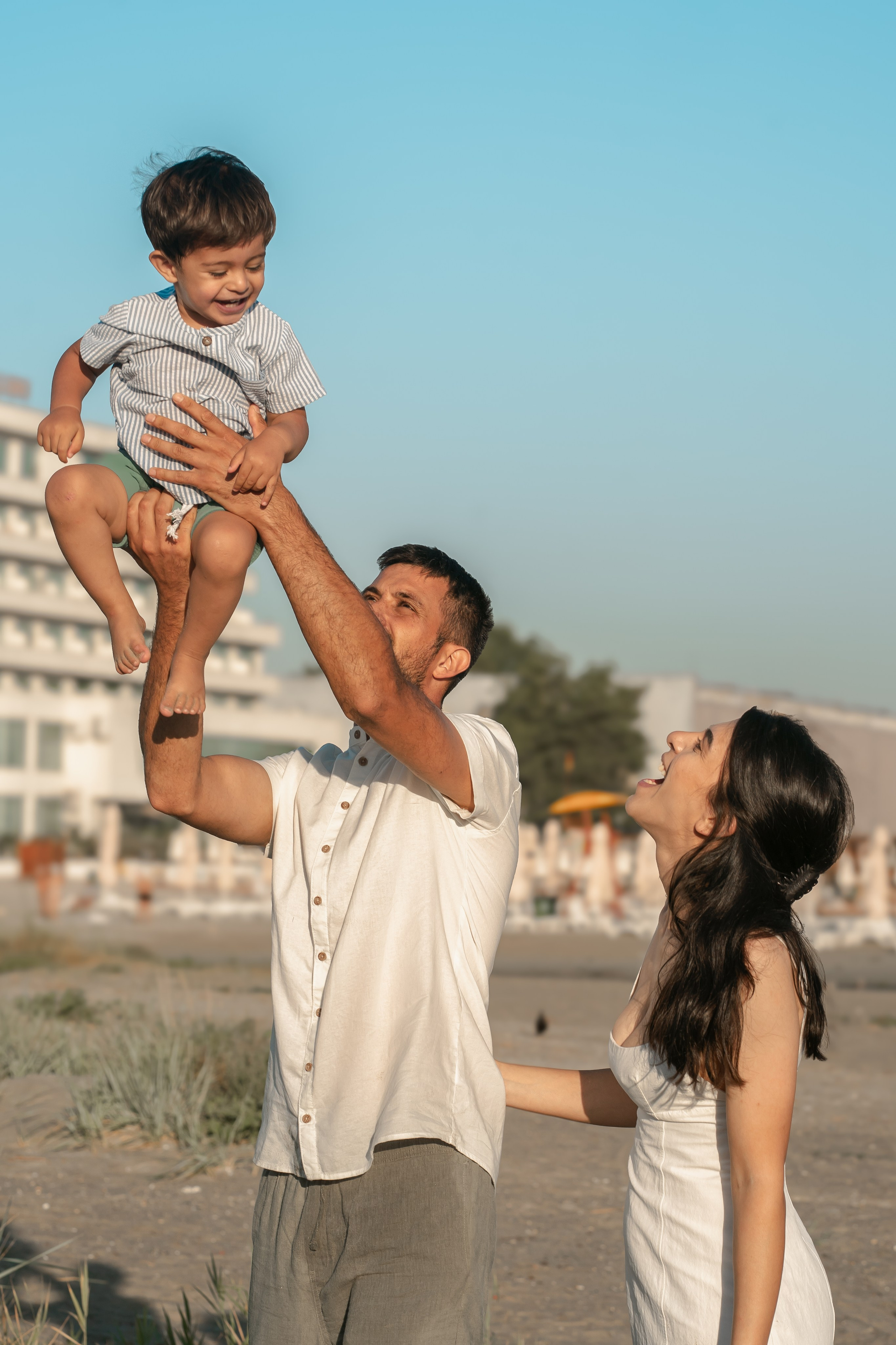 familie care se joaca cu copilul pe plaja