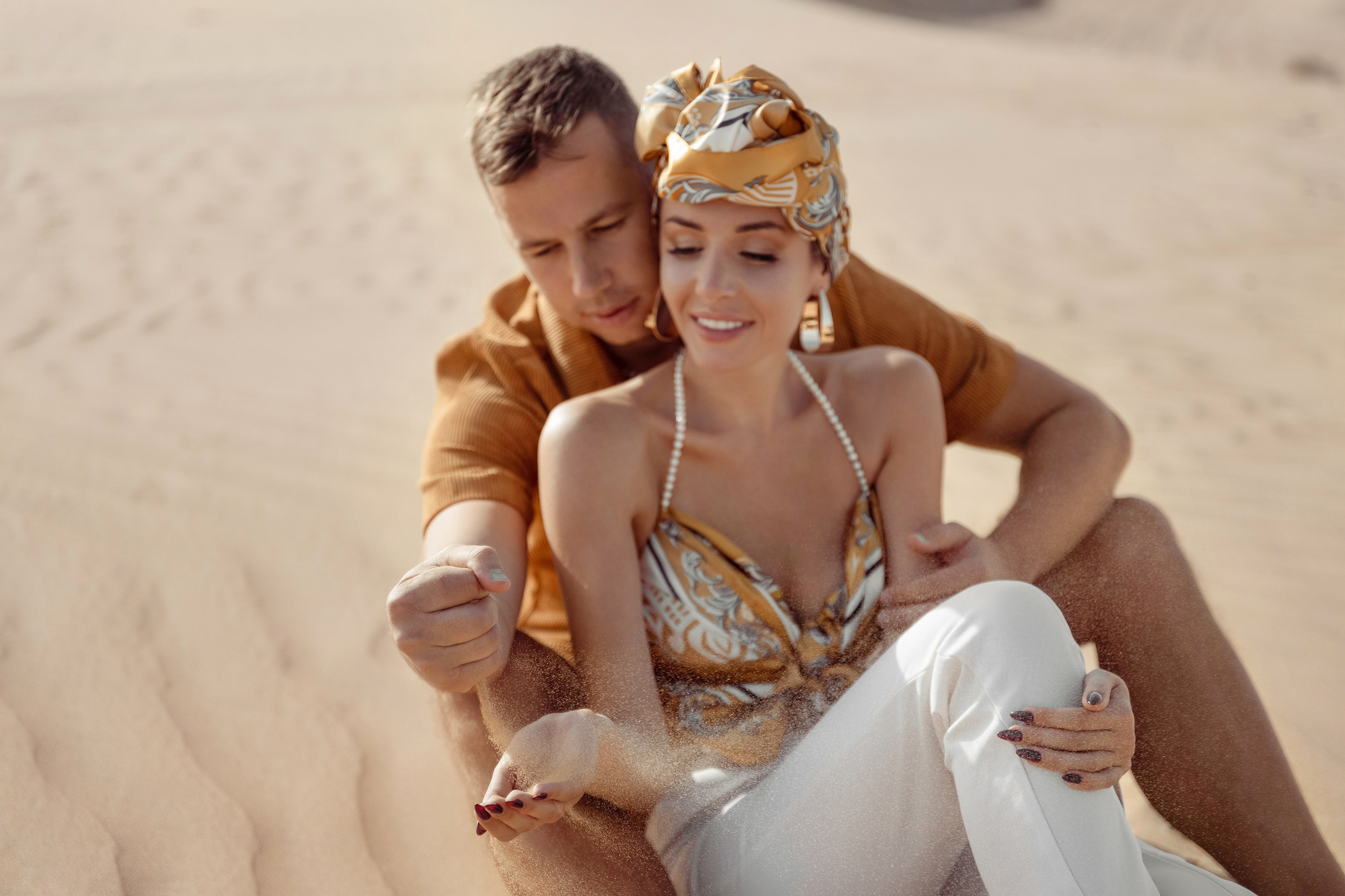 A couple shares a spontaneous, joyful moment in the desert, their embrace reflecting the warmth and beauty of the surrounding nature. Dubai, United Arab Emirates