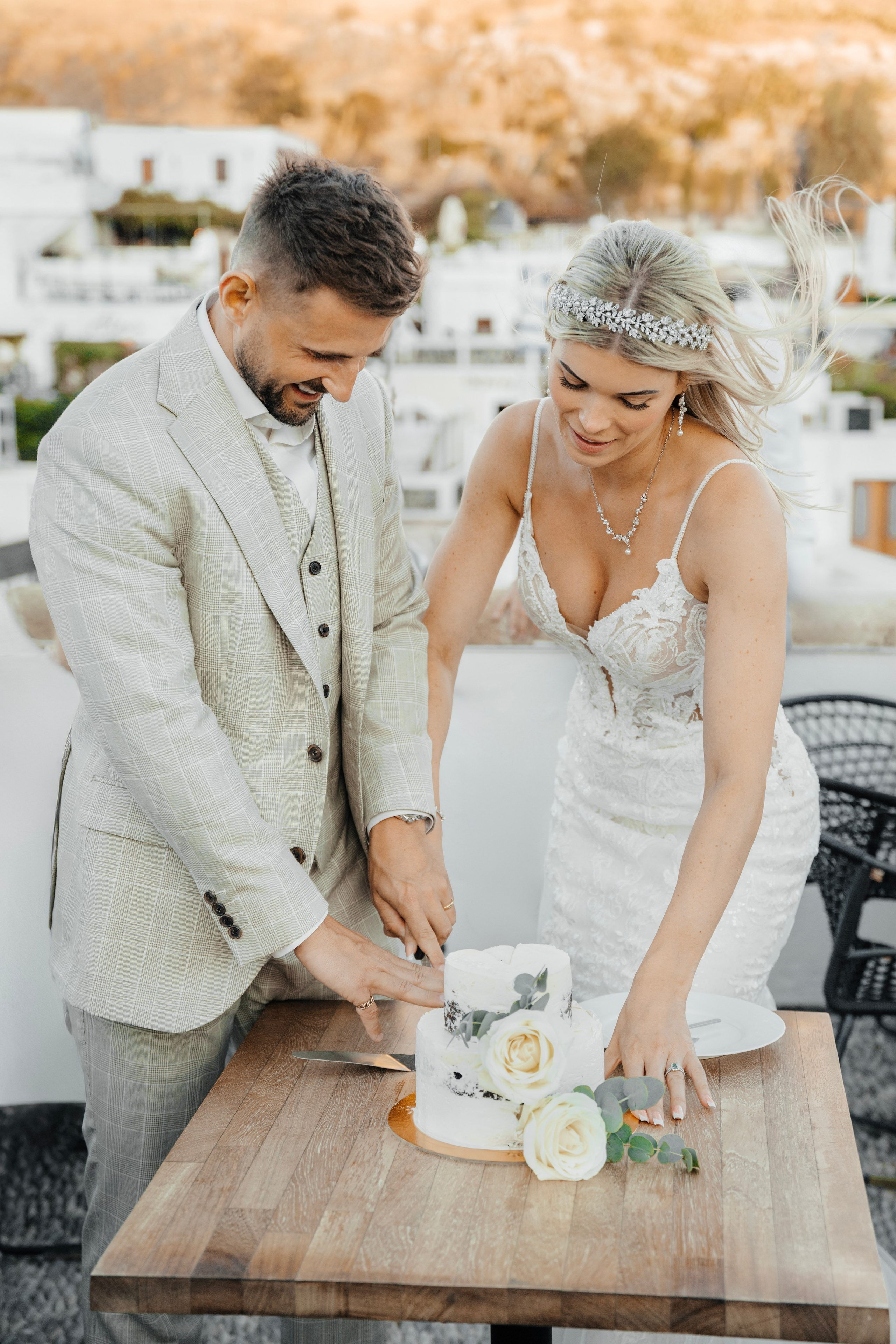 A Groom and a bride are cutting Wedding cake at a rustic bar in Lindos, Greece.