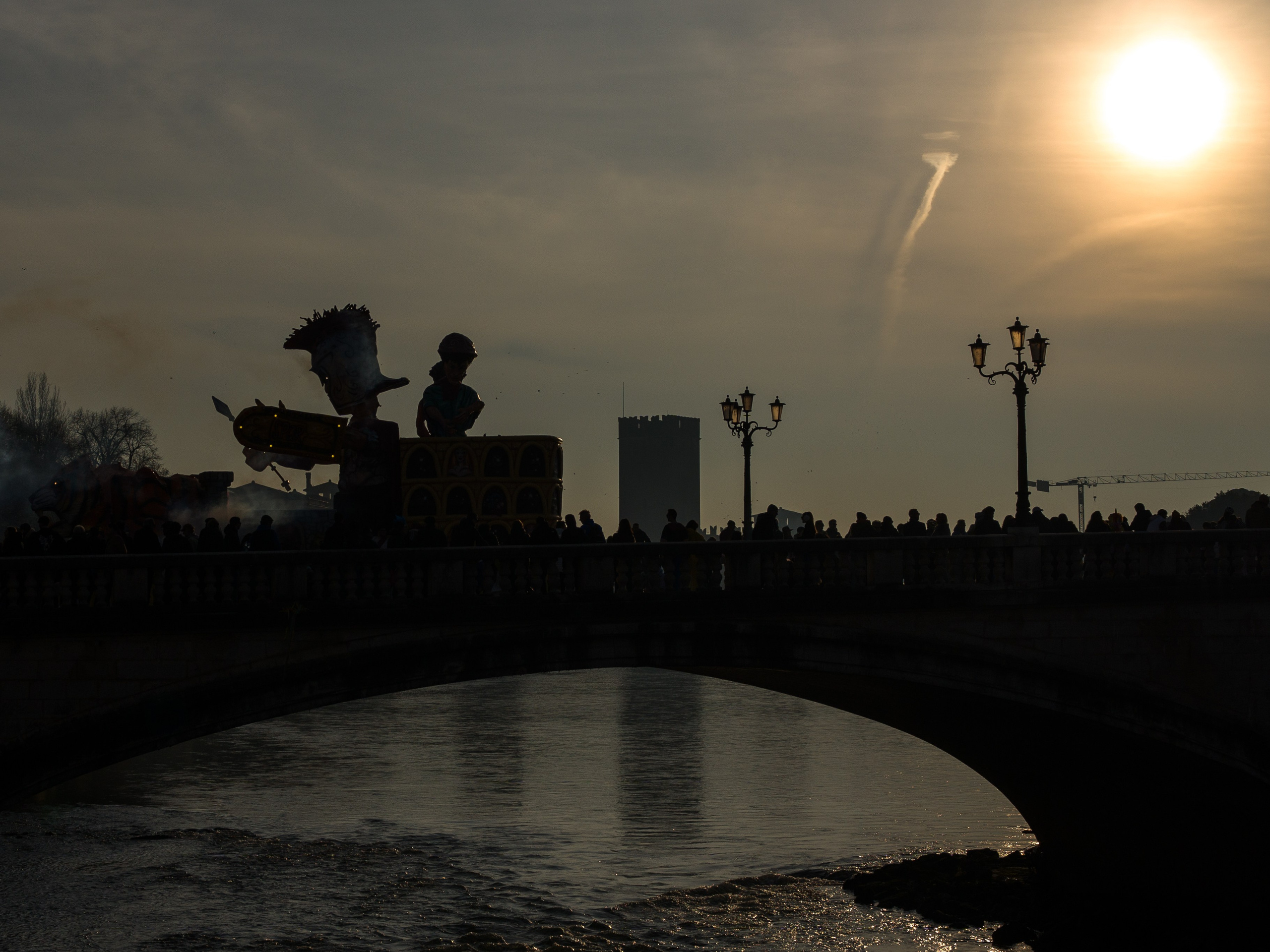 Carnival silhouette on Ponte Pietra bridge at sunset in Verona with warm light over the Adige river