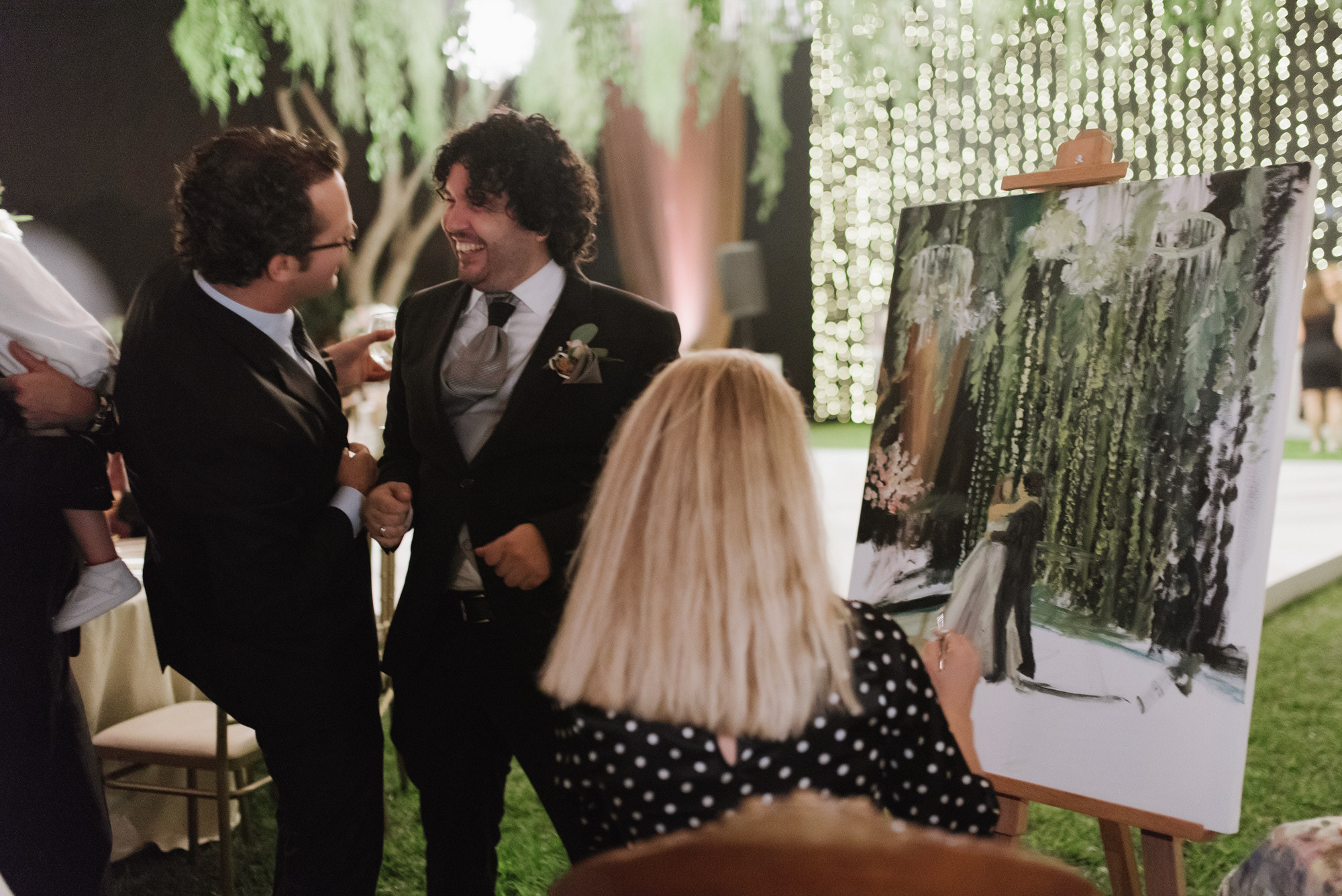 a couple of people standing around a painting