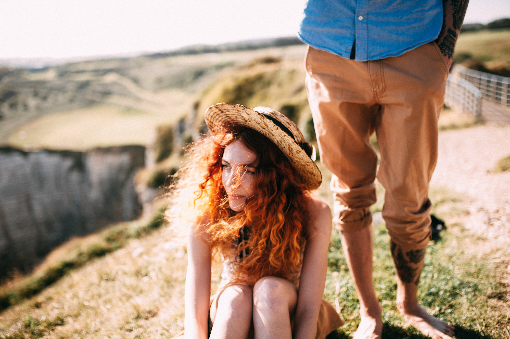 a woman sitting on the ground with a man standing behind her