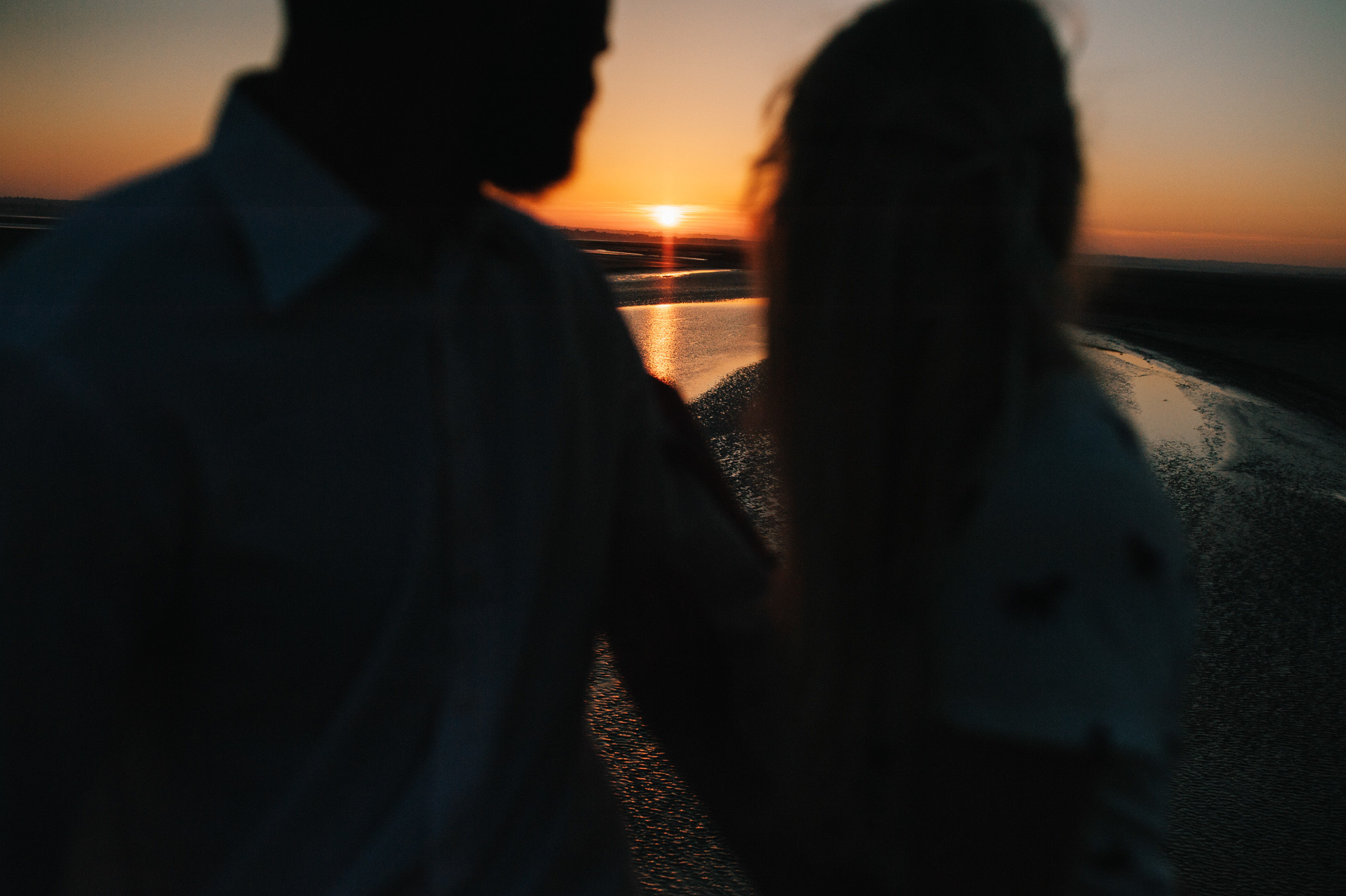 a couple walking on a beach at sunset