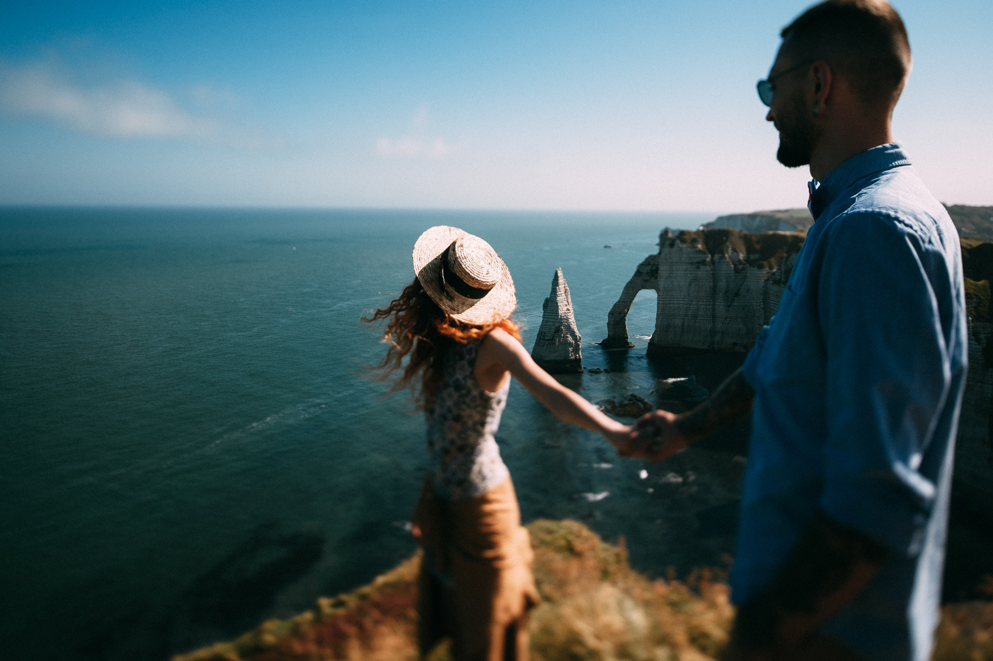 a man and woman standing on a cliff overlooking the ocean