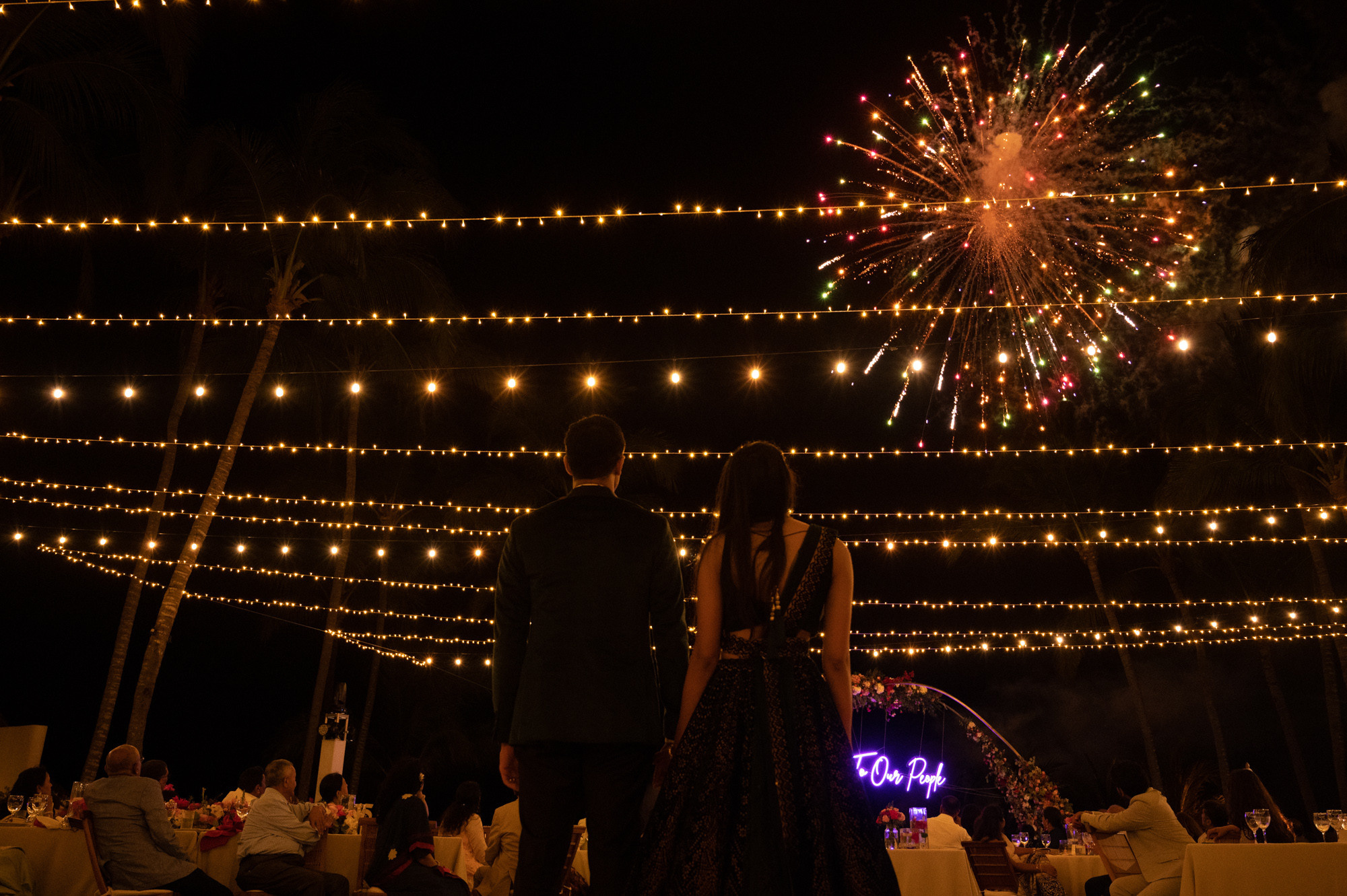a couple standing in front of a fireworks