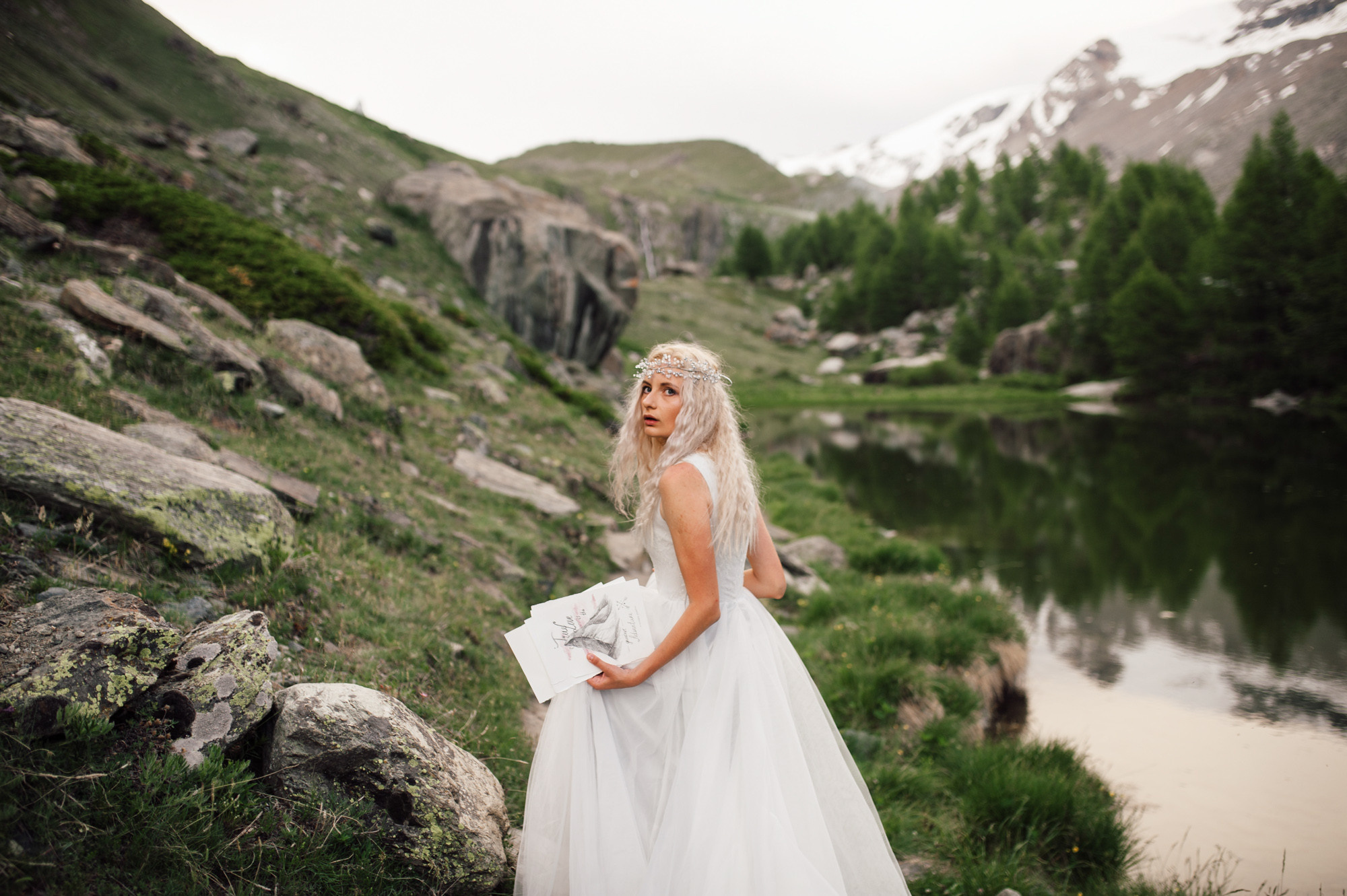 a bride in a white dress standing on a rocky mountain