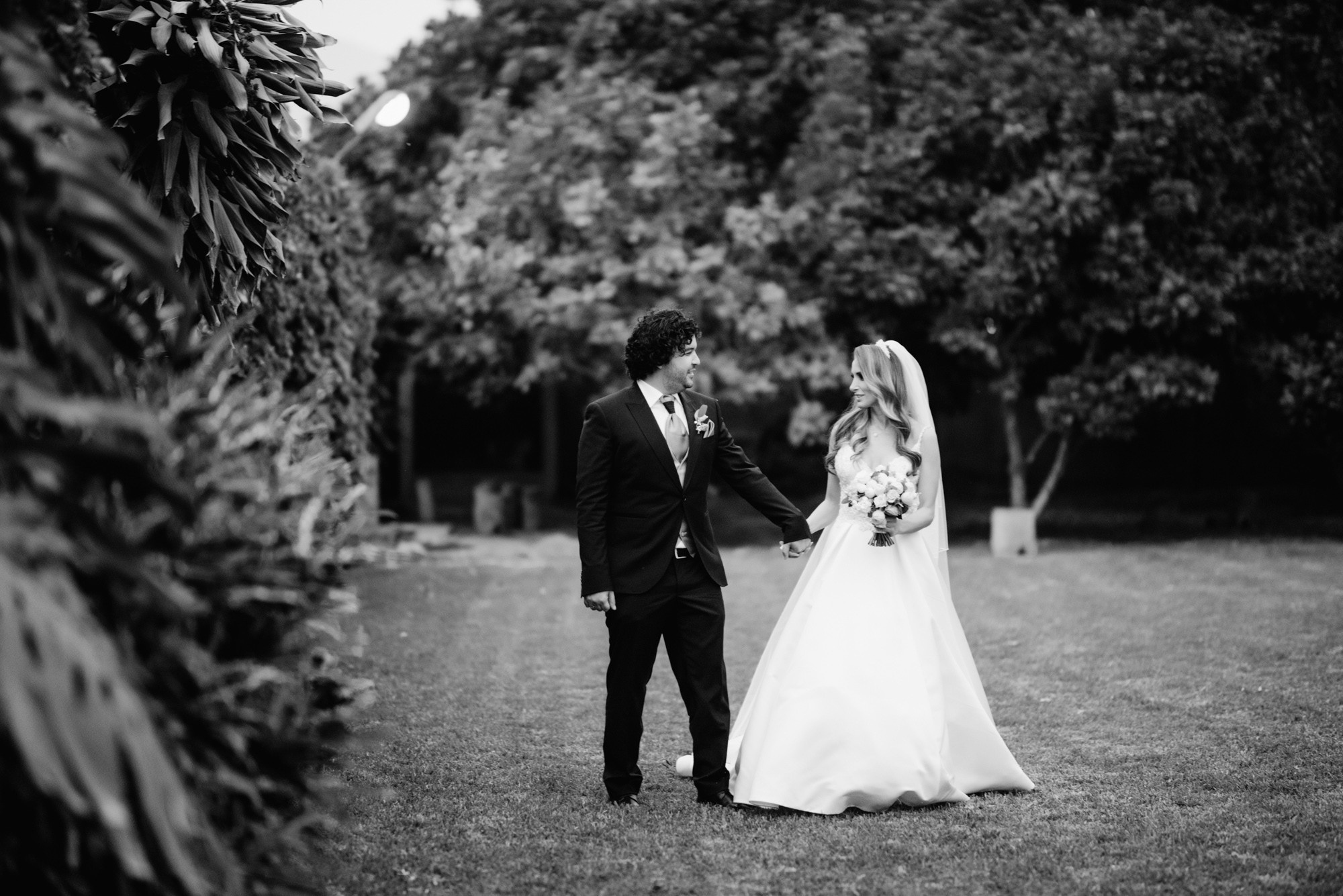 a bride and groom walking through the grass
