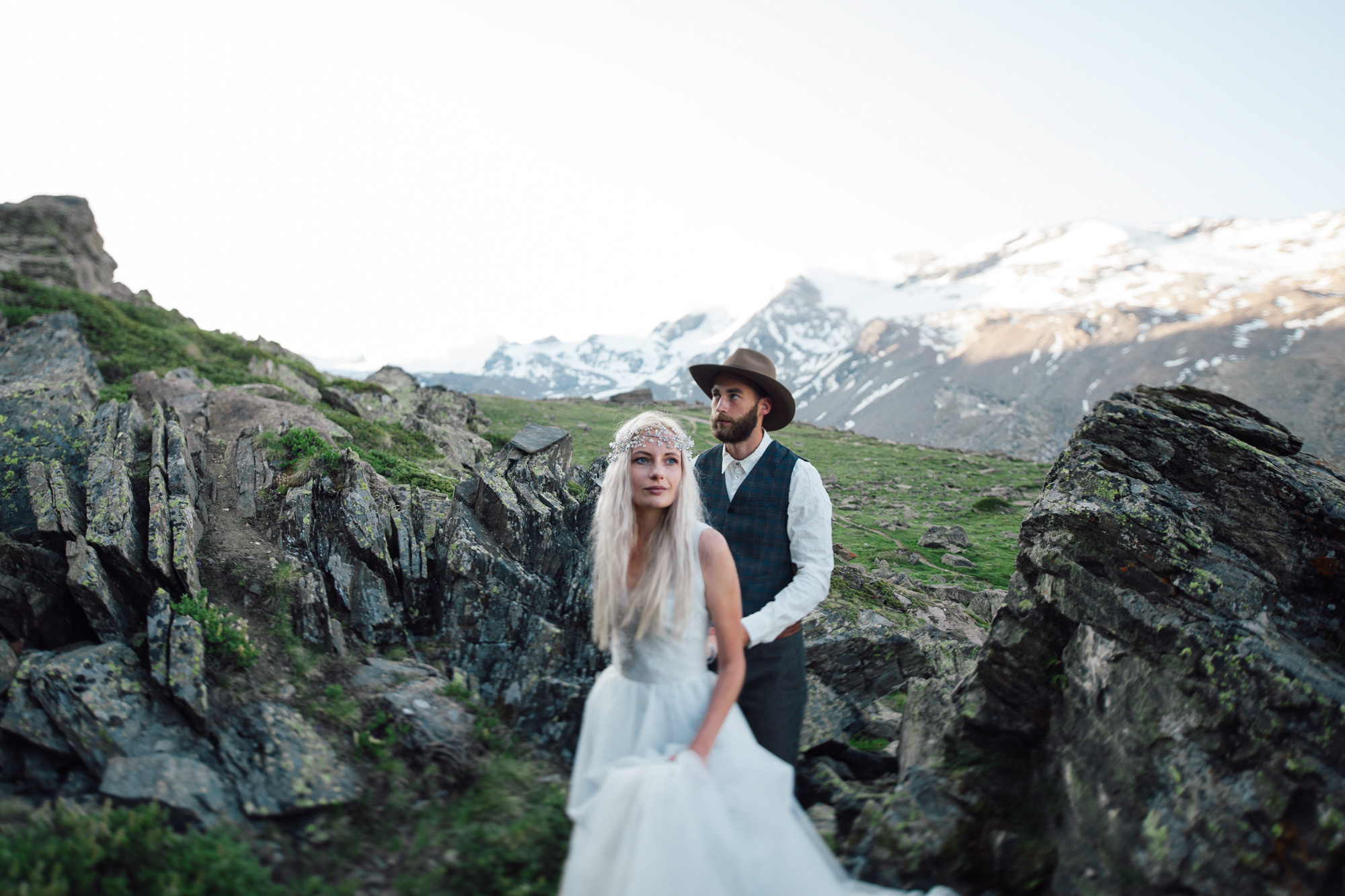 a bride and groom standing on a rocky mountain