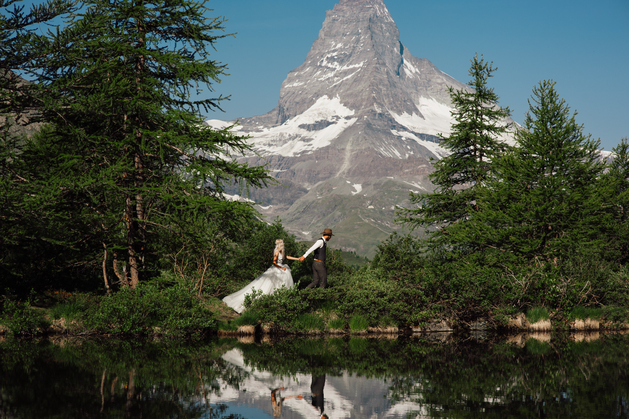 a bride and groom standing in front of a mountain