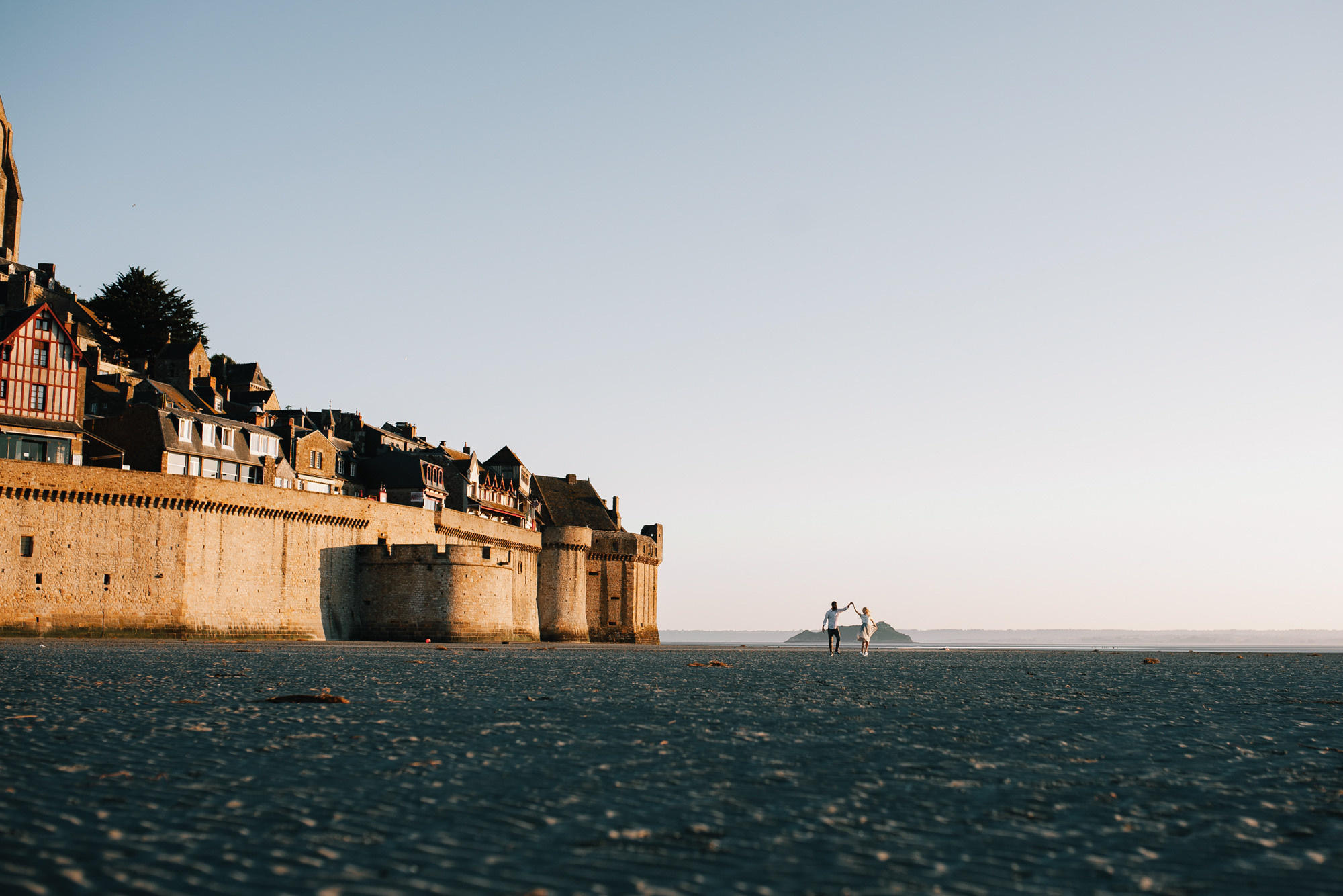 a man walking on a beach next to a castle