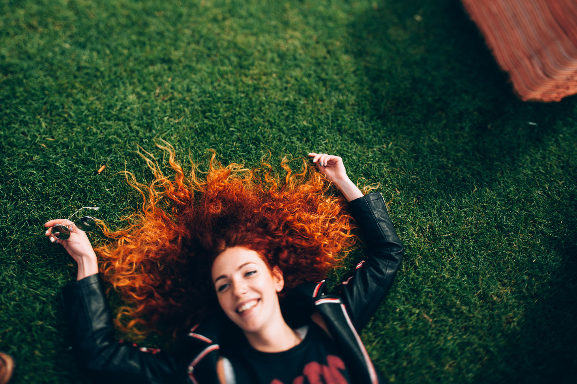 a woman laying on the grass with her hair blowing
