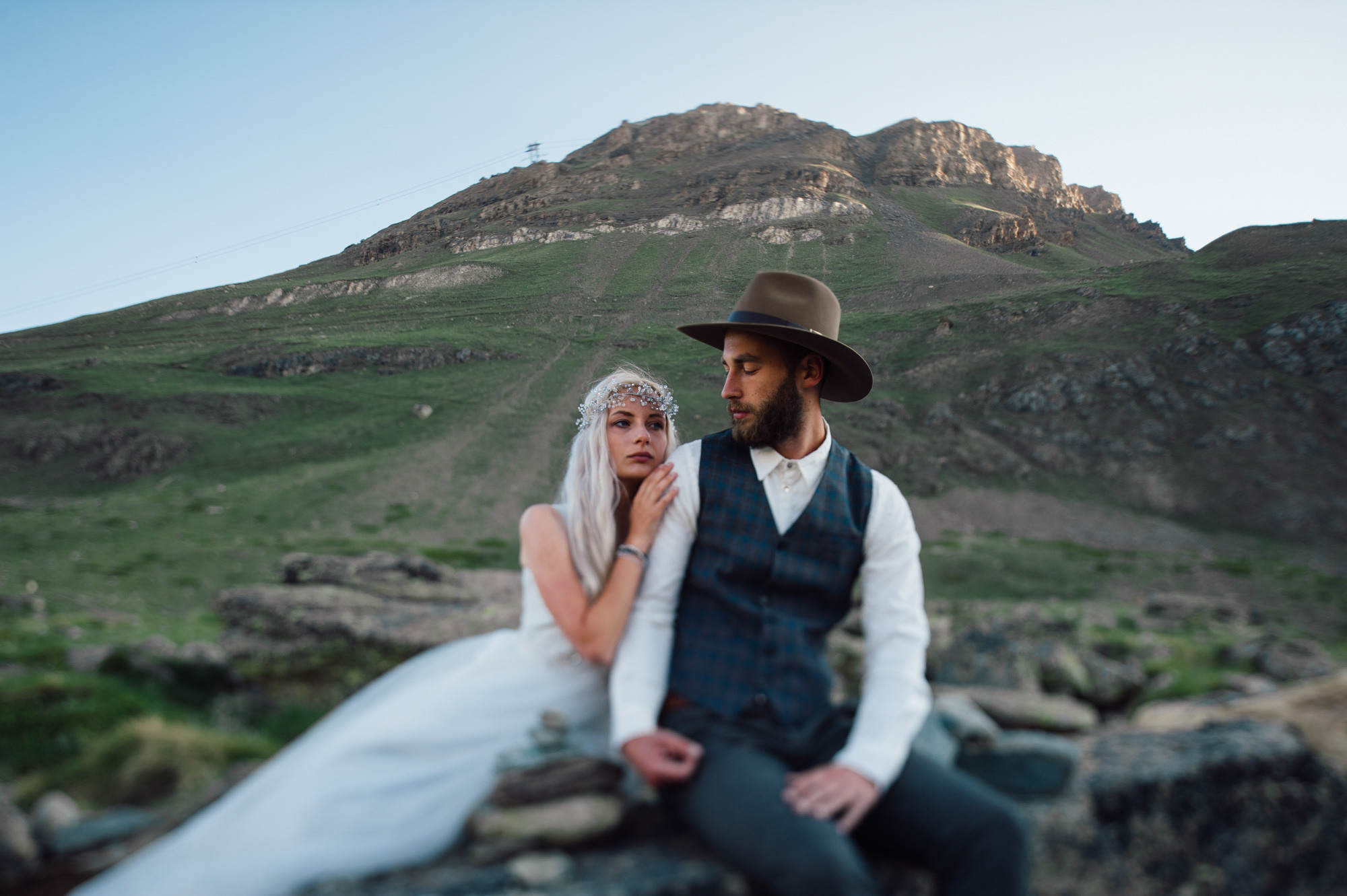 a bride and groom sitting on a rock
