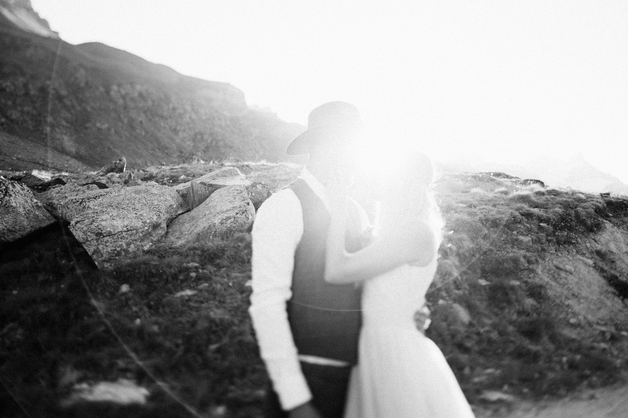 a bride and groom standing on a rocky beach
