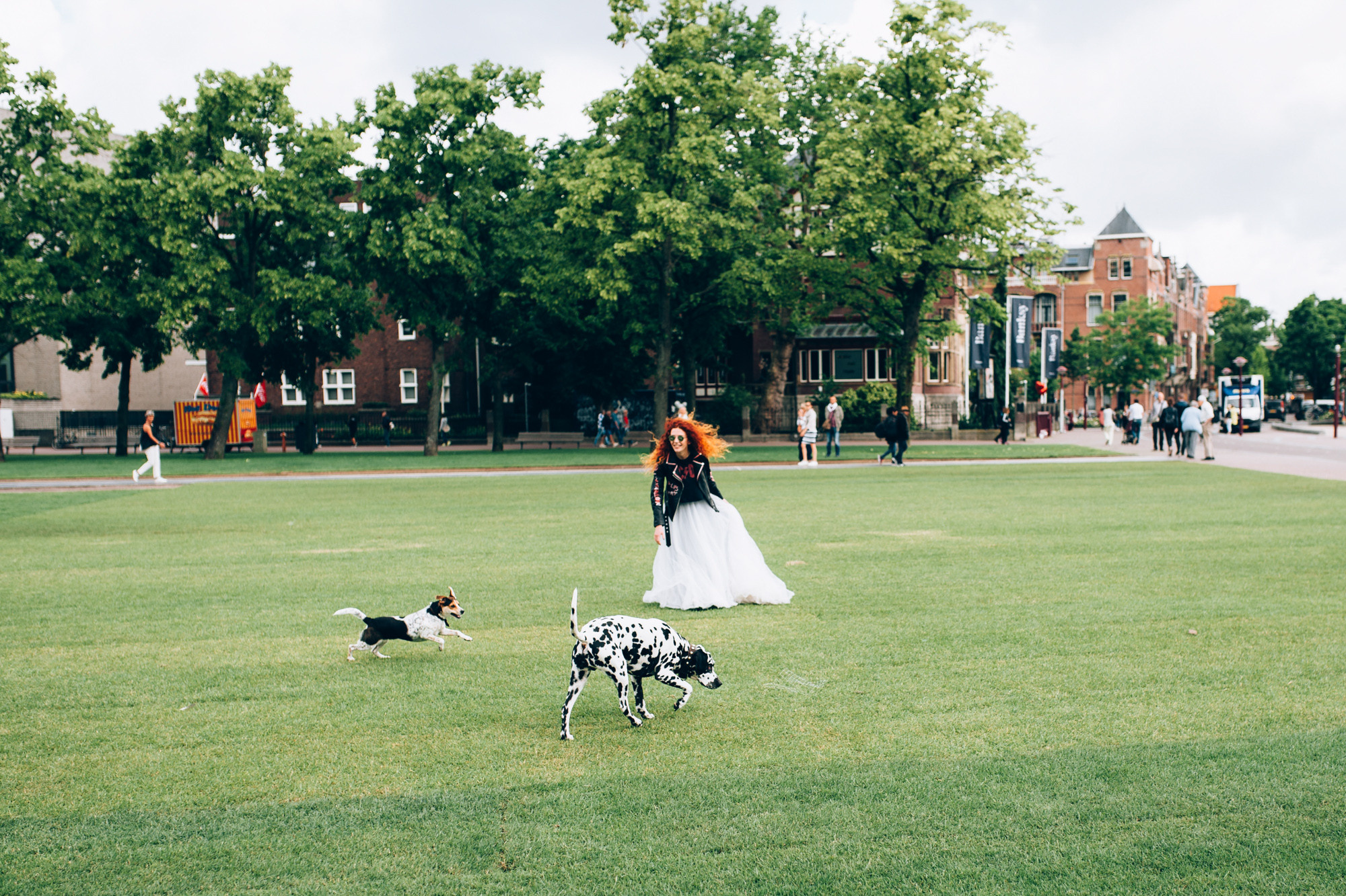 a woman in a white dress is walking a dog