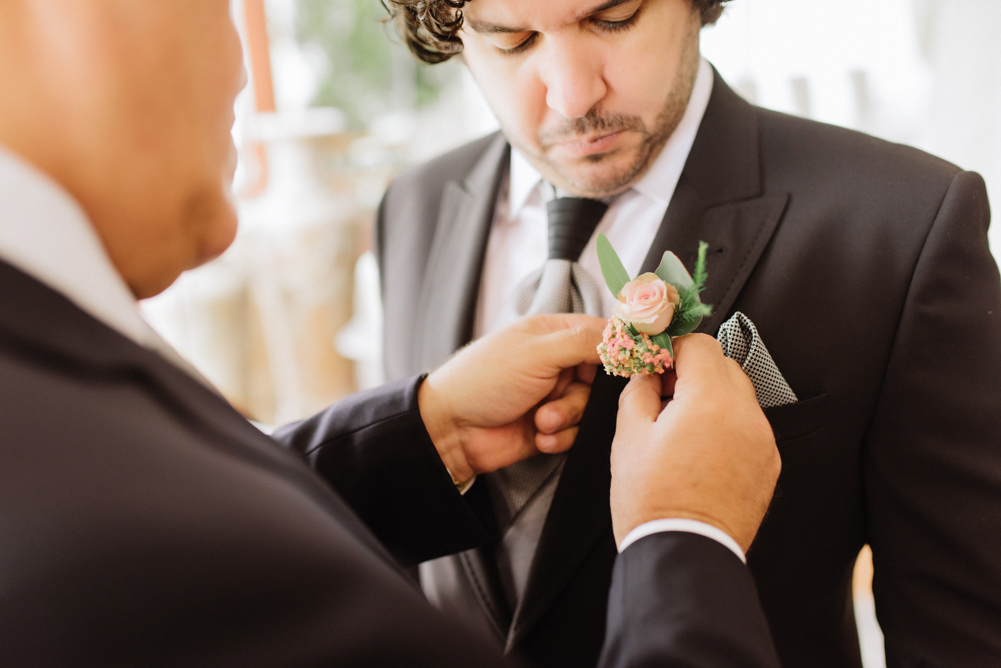 a man in a suit adjusting a flower