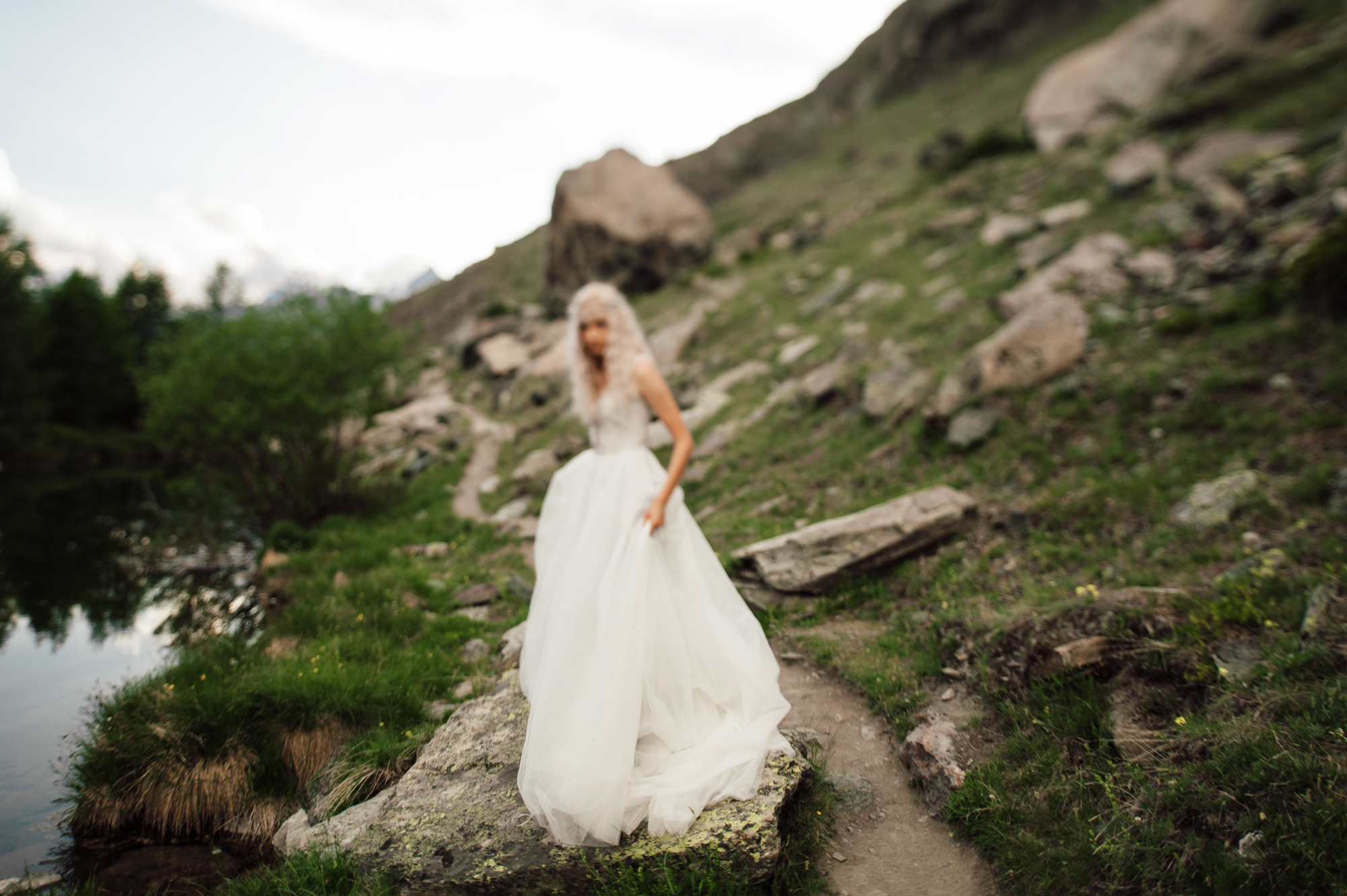 a woman in a wedding dress standing on a rocky hillside