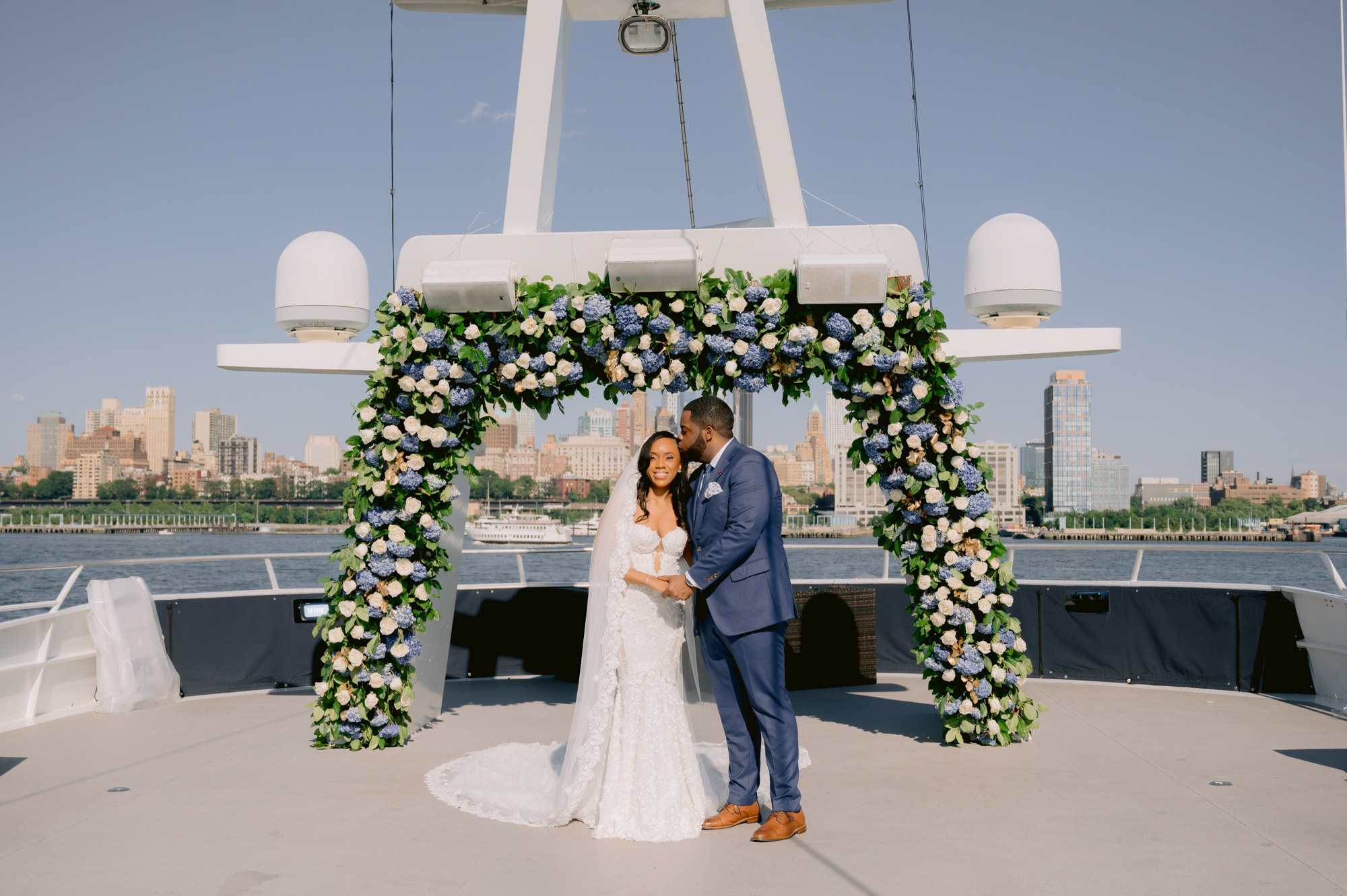 a bride and groom pose for a photo on the deck of a boat