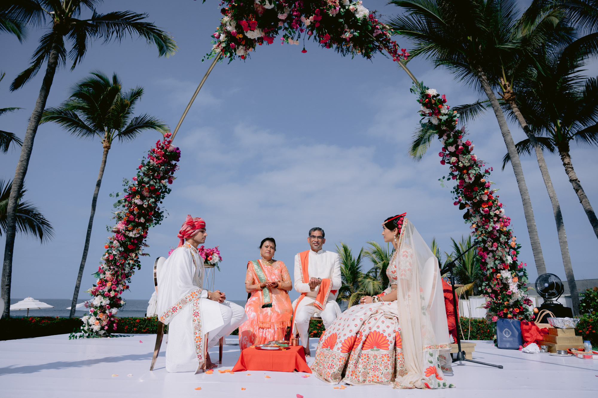 a couple sitting on a white table under palm trees