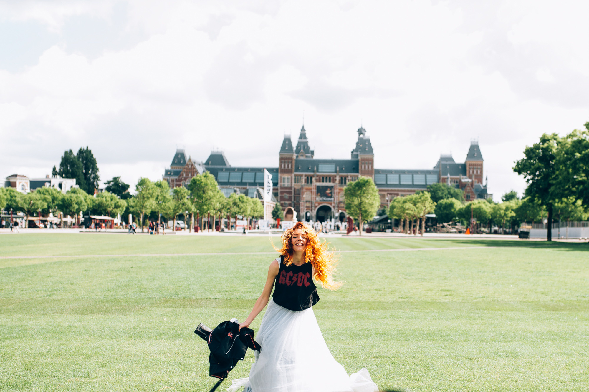 a woman in a white dress and black shoes walking across a green field