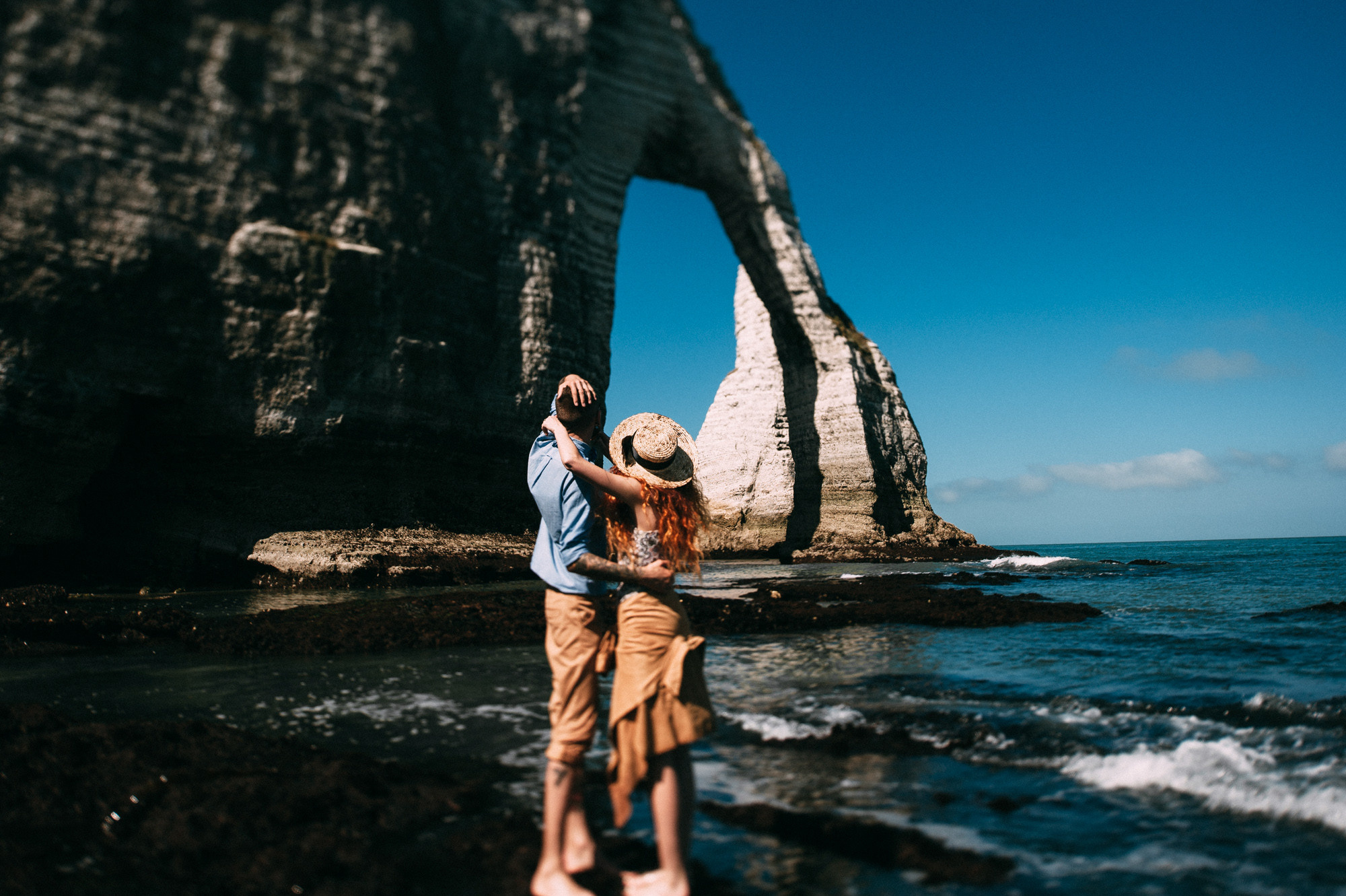 a man and woman standing on a rocky beach