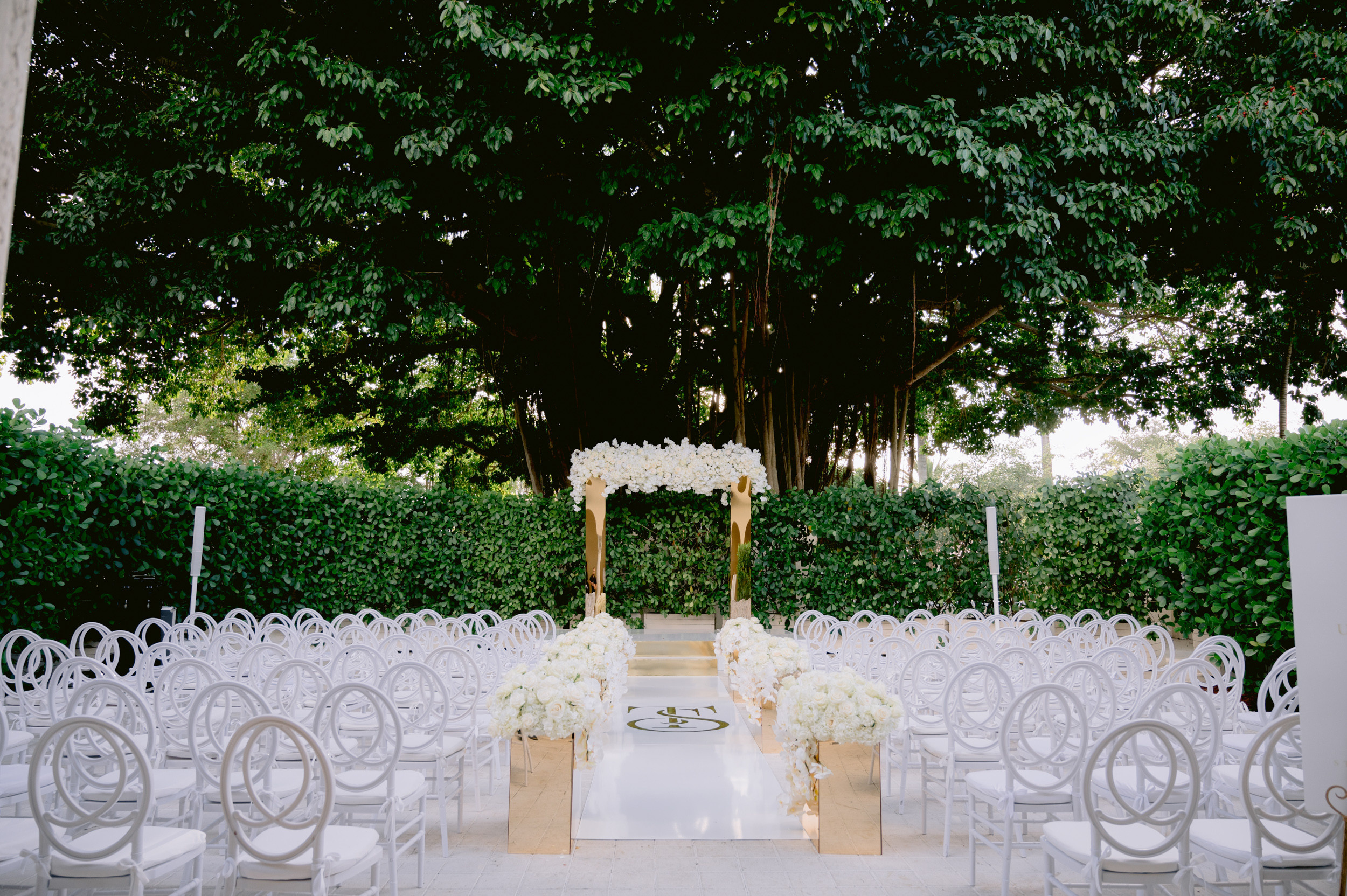 a white ceremony setup with white chairs and white flowers