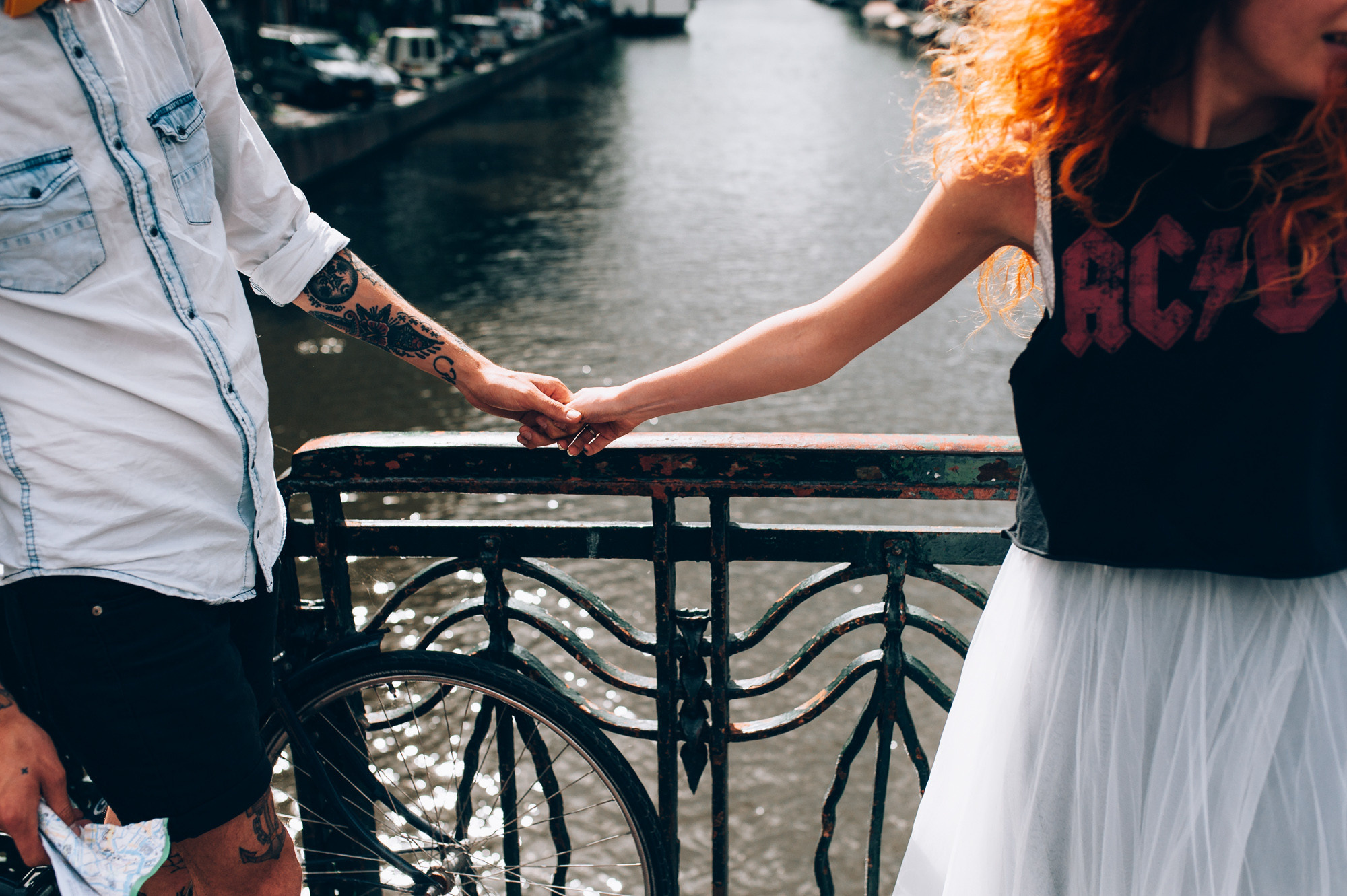 a man and woman holding hands on a bridge