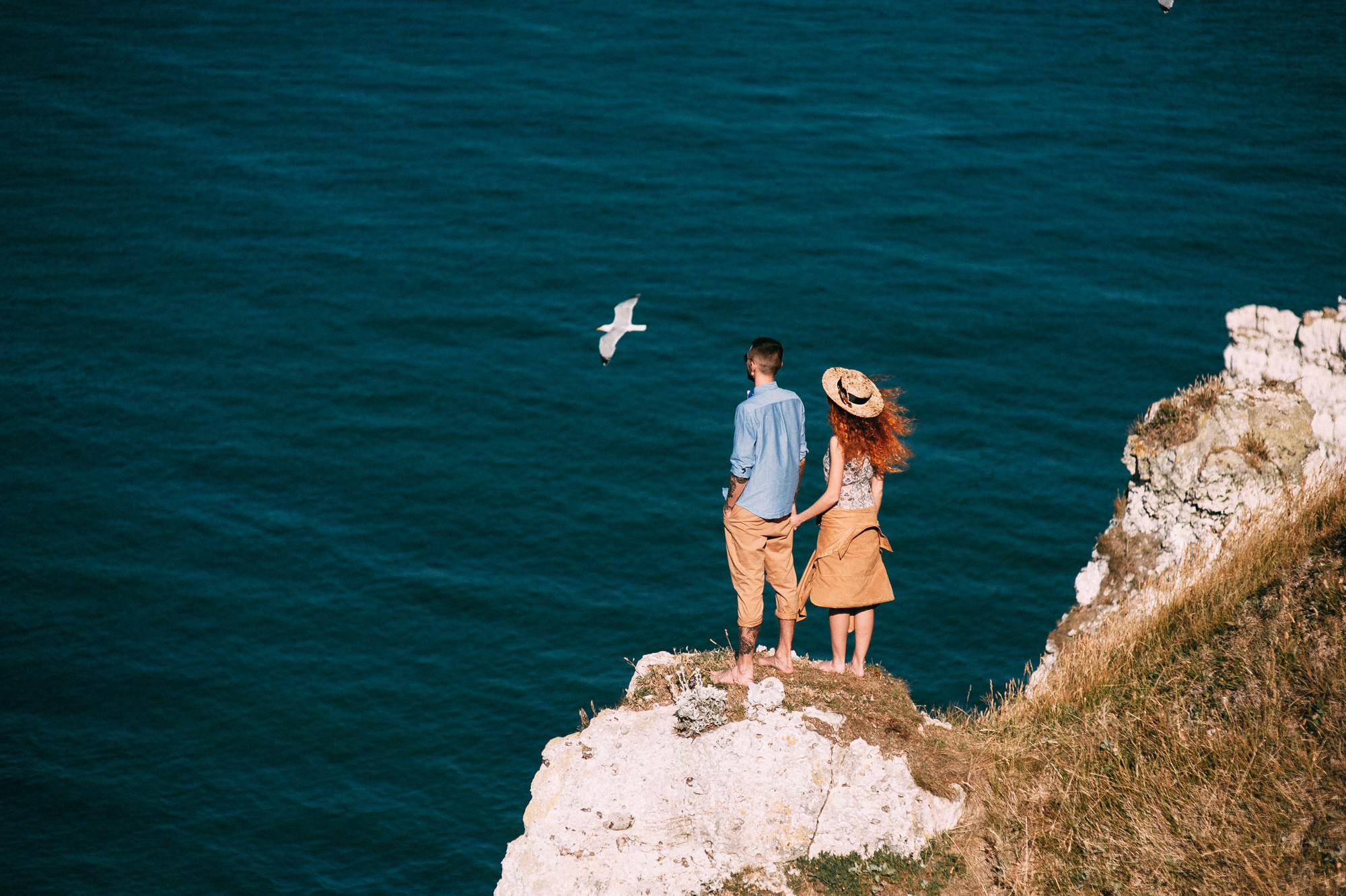 a couple standing on a cliff overlooking the ocean