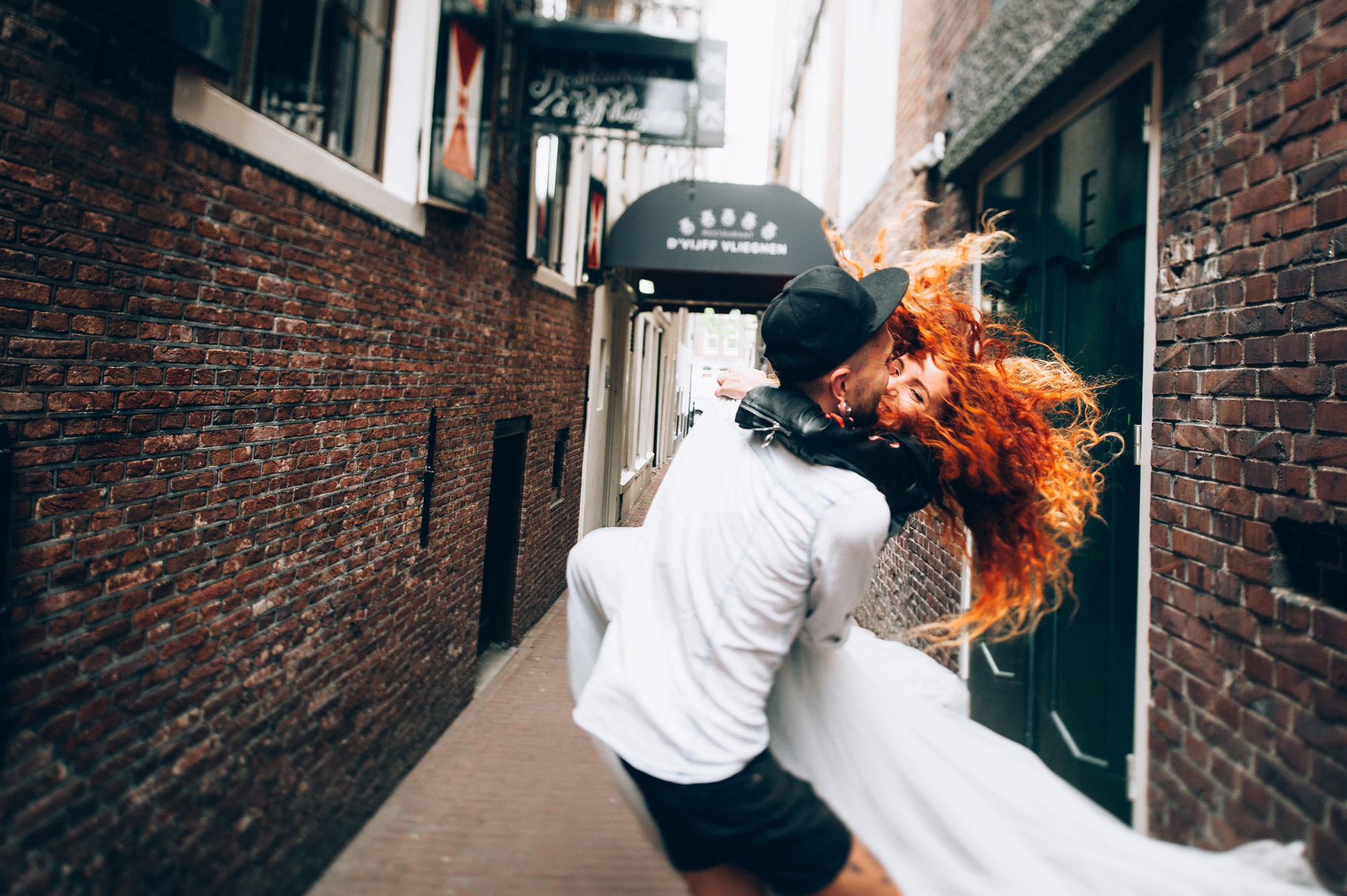 a woman with red hair is walking down a narrow street