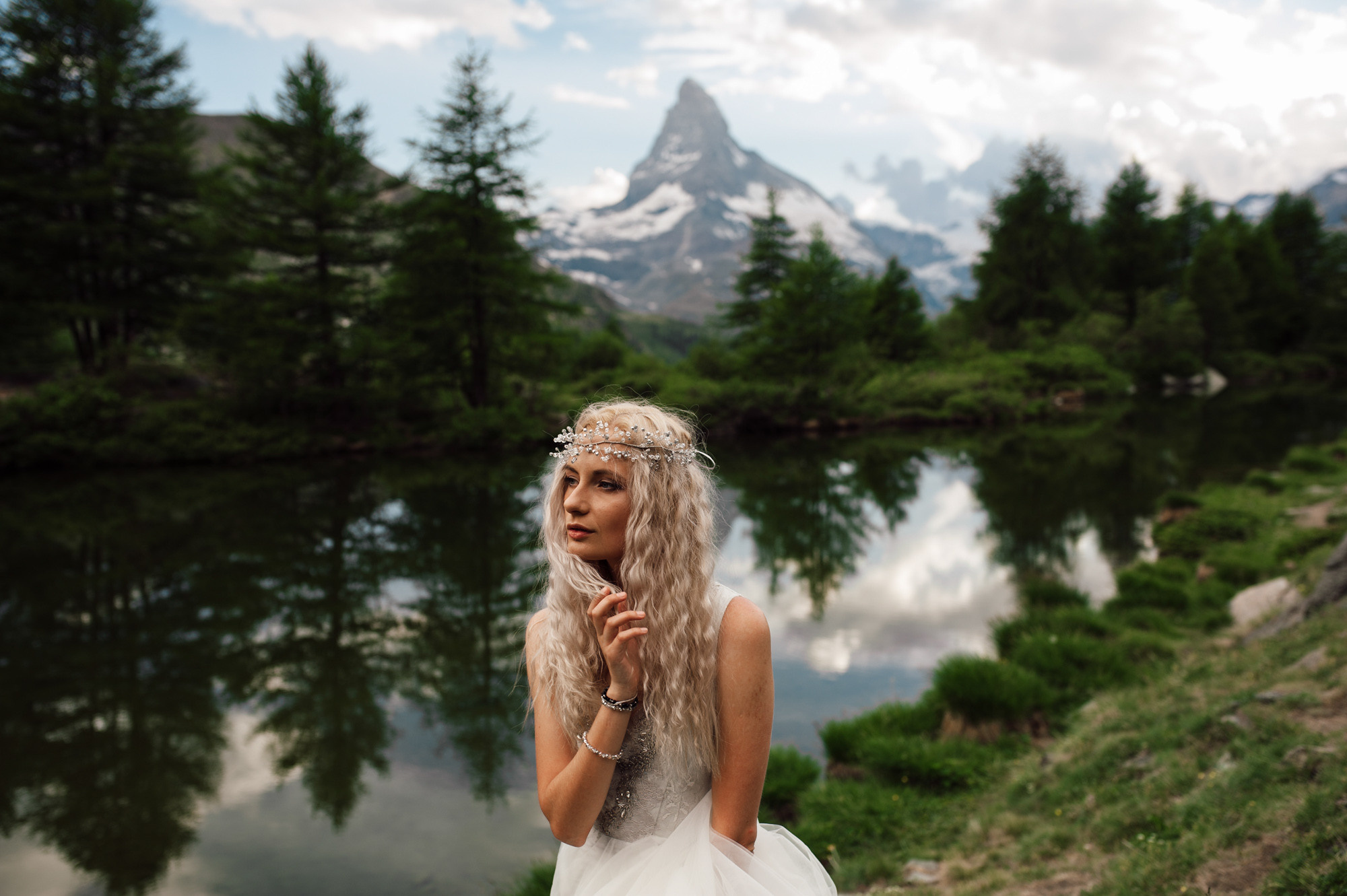 a woman in a wedding dress standing by a lake