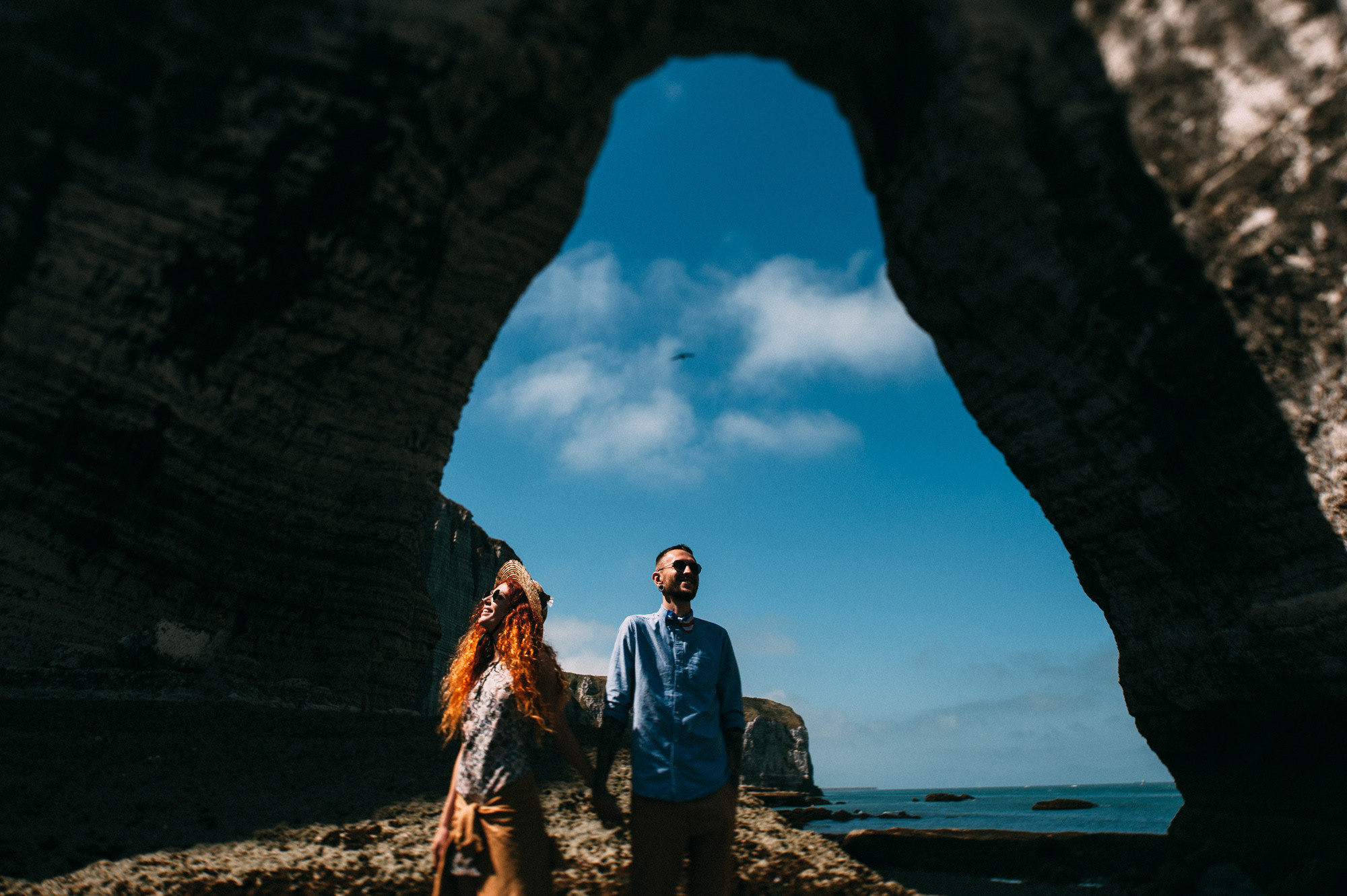 a couple standing in a cave on the beach