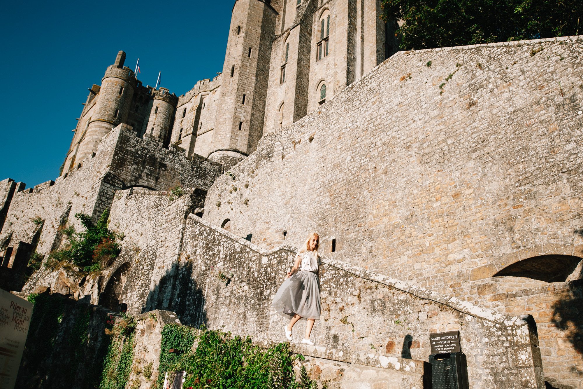a woman standing on a stone wall in front of a castle