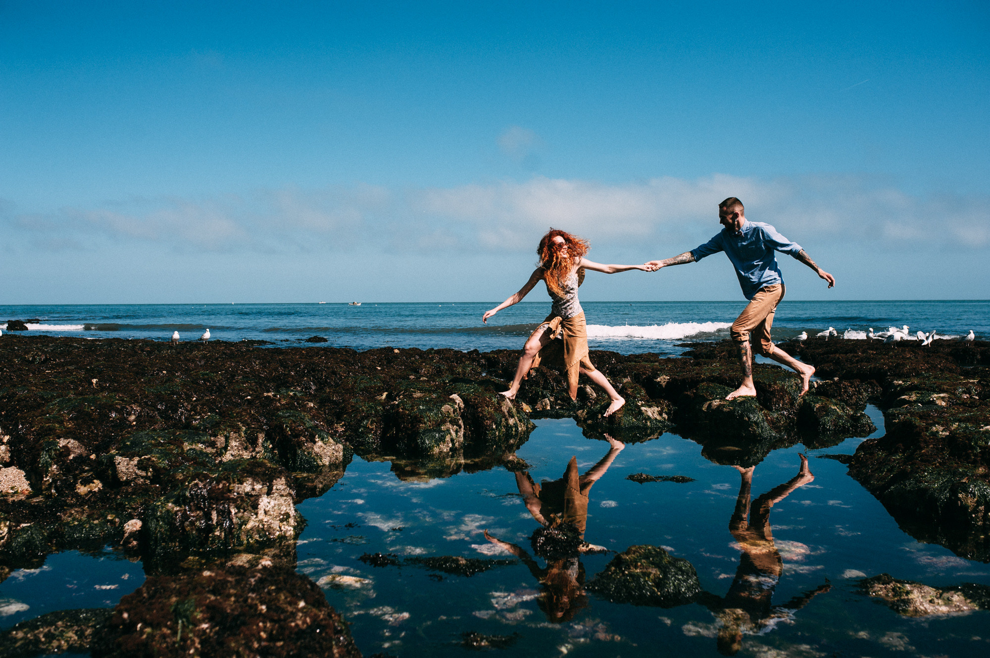 a couple running through the water on a beach