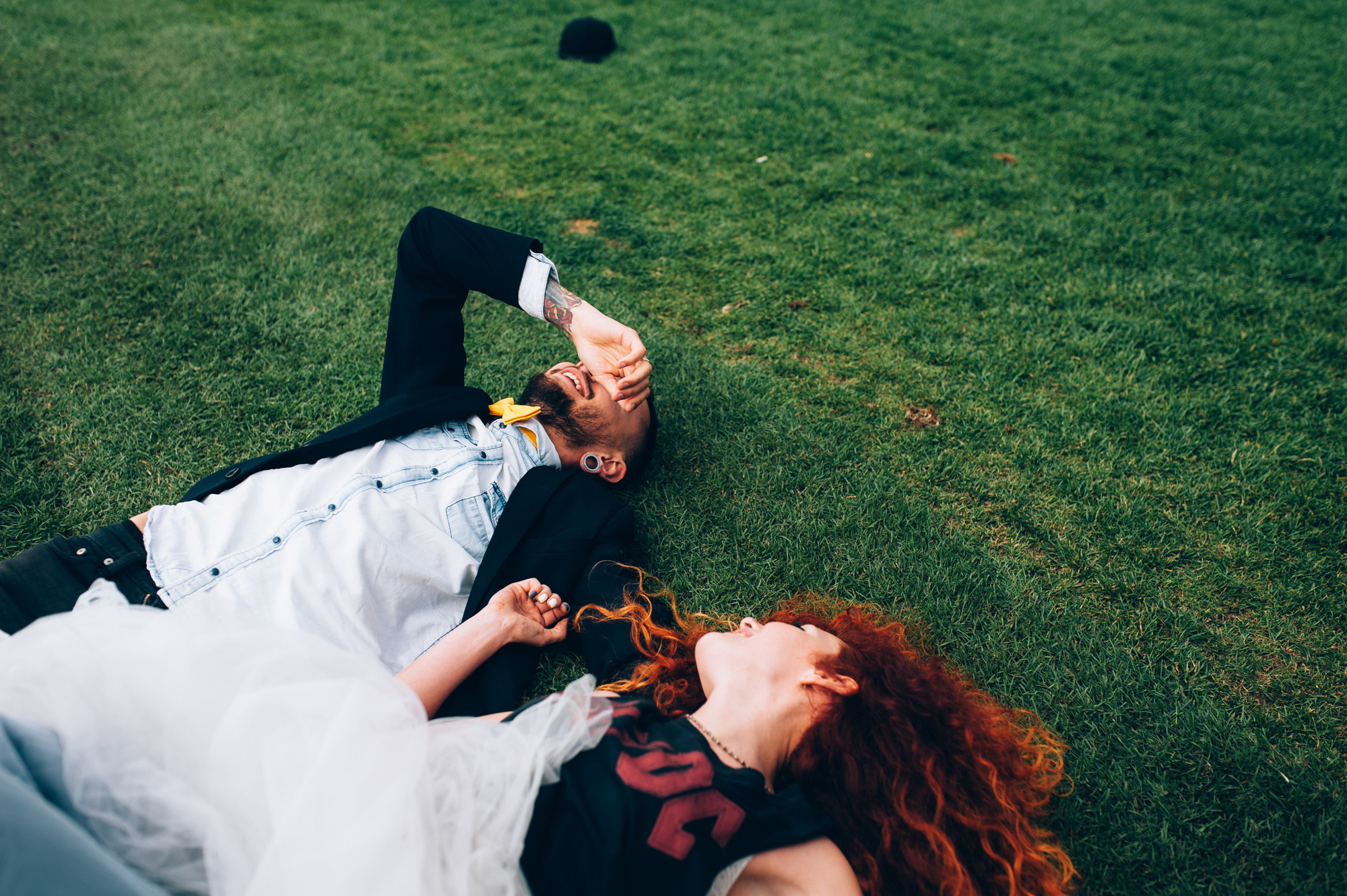 a bride and groom laying on the grass