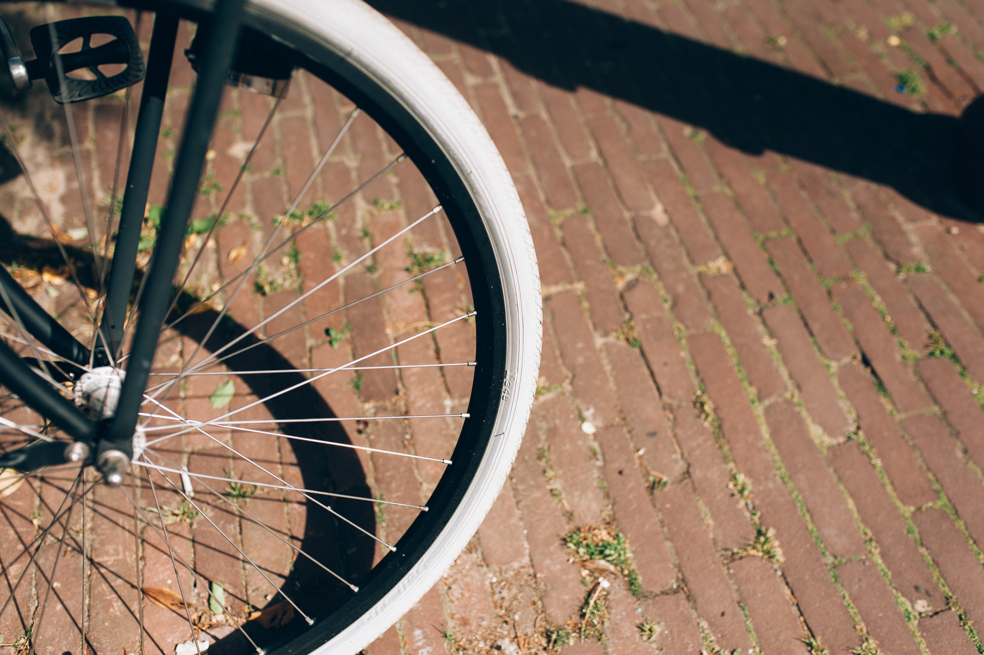 a bicycle wheel on a brick sidewalk