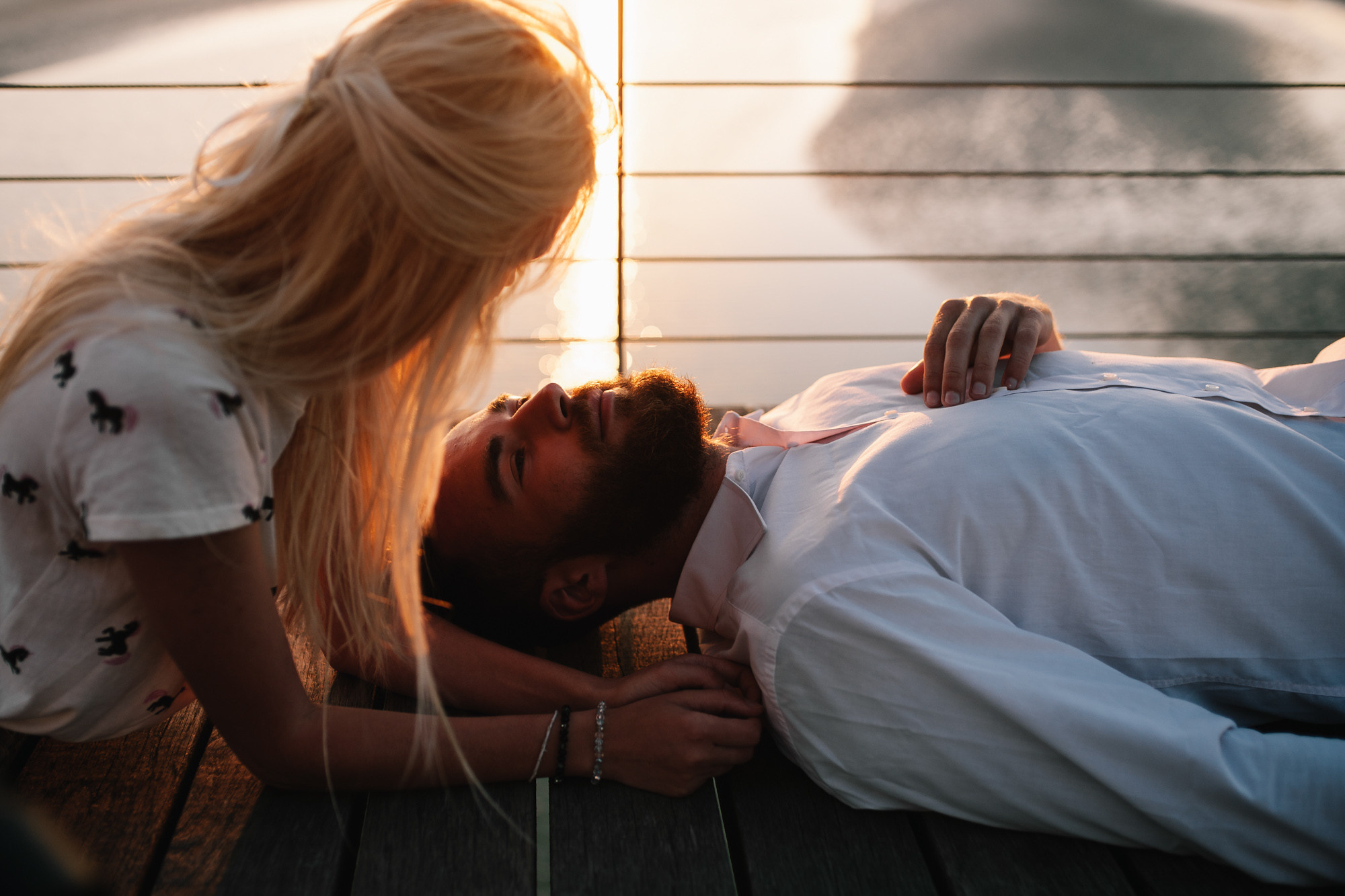 a man and woman laying on a wooden bench