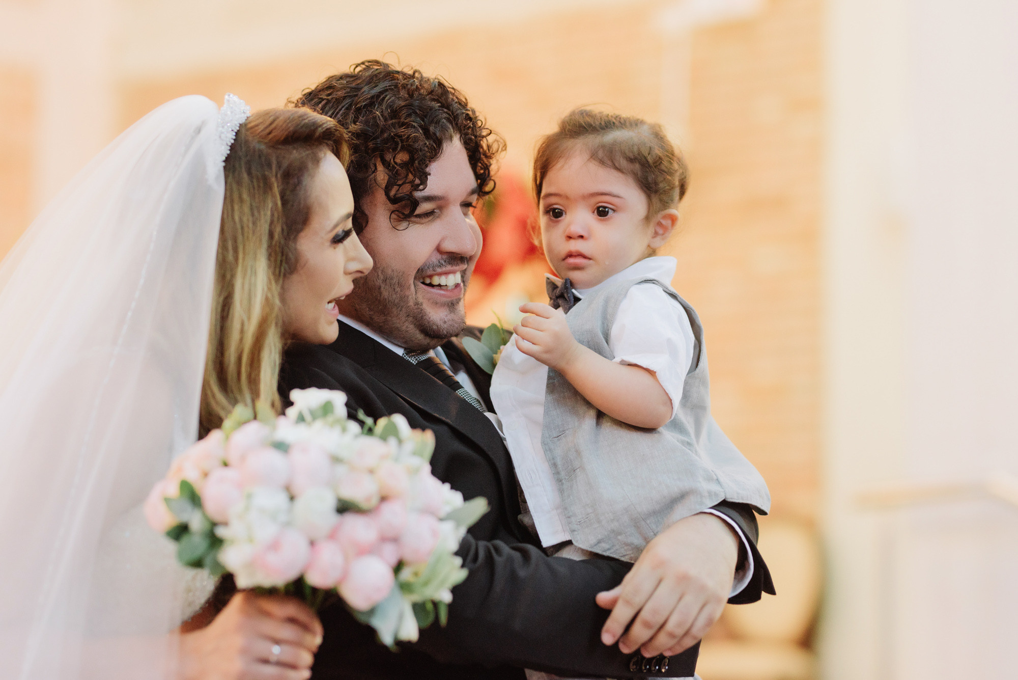 a man holding a baby while he holds a bouquet