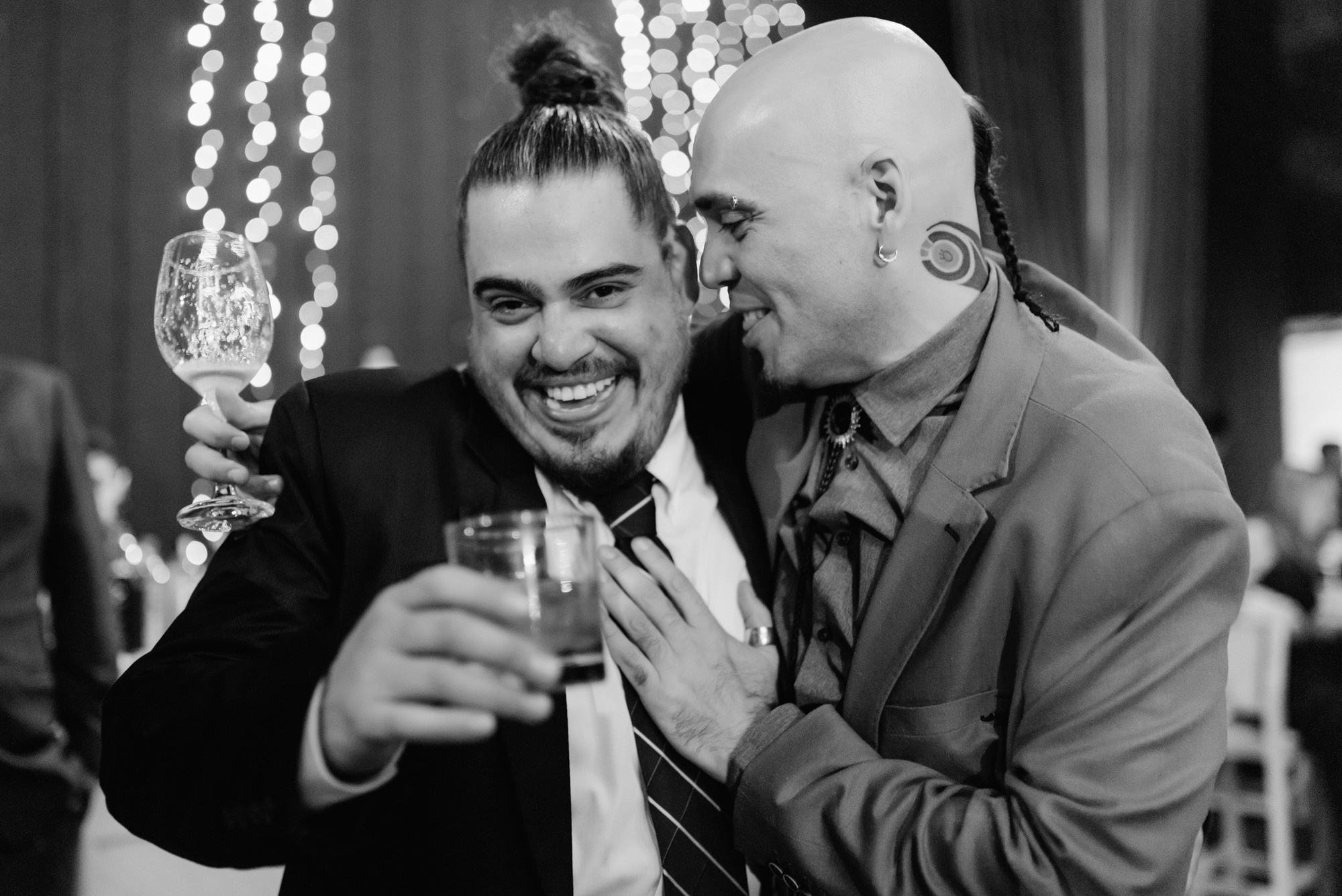 two men are smiling and drinking wine at a party