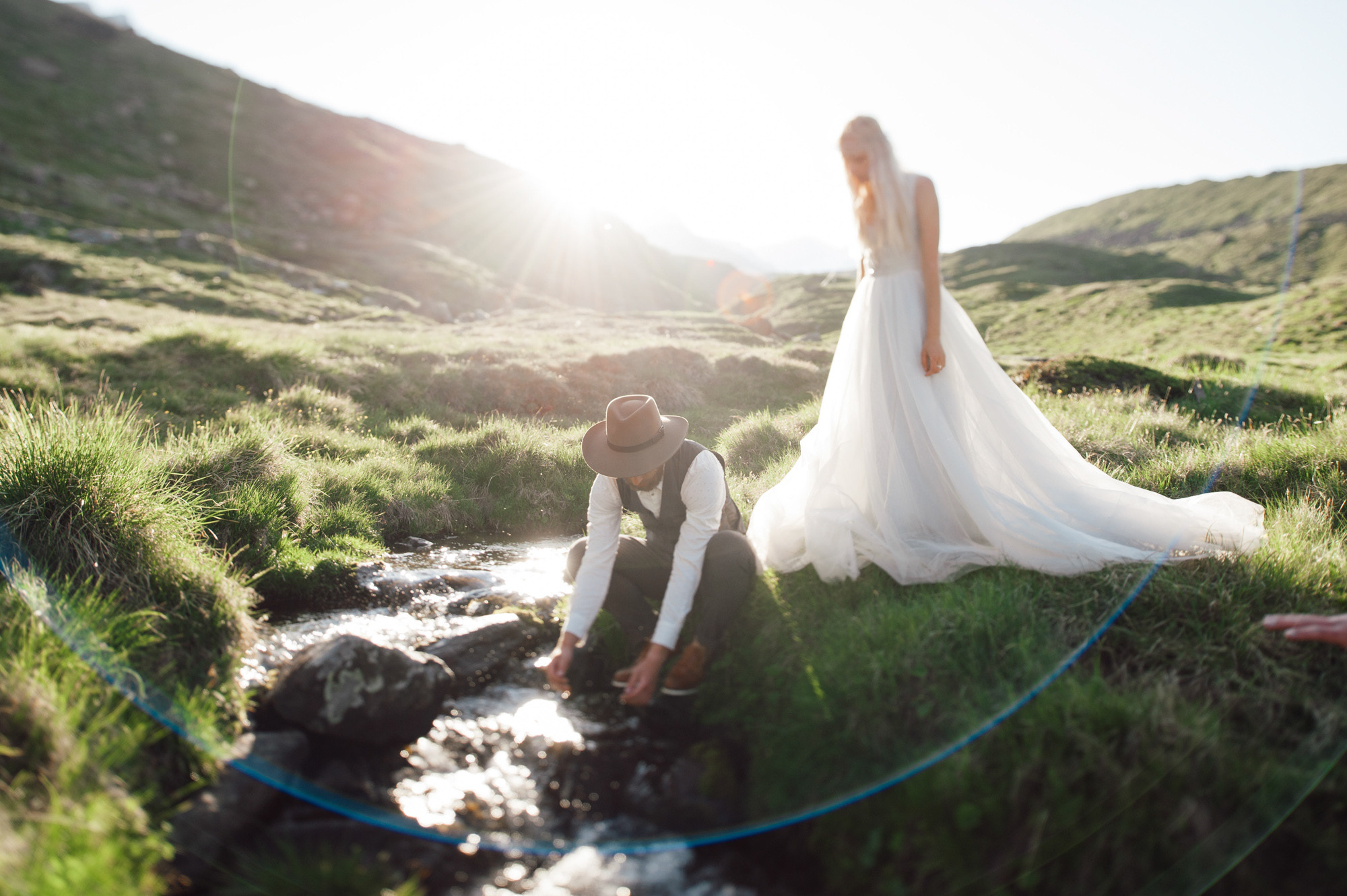 a bride and groom are sitting in the grass