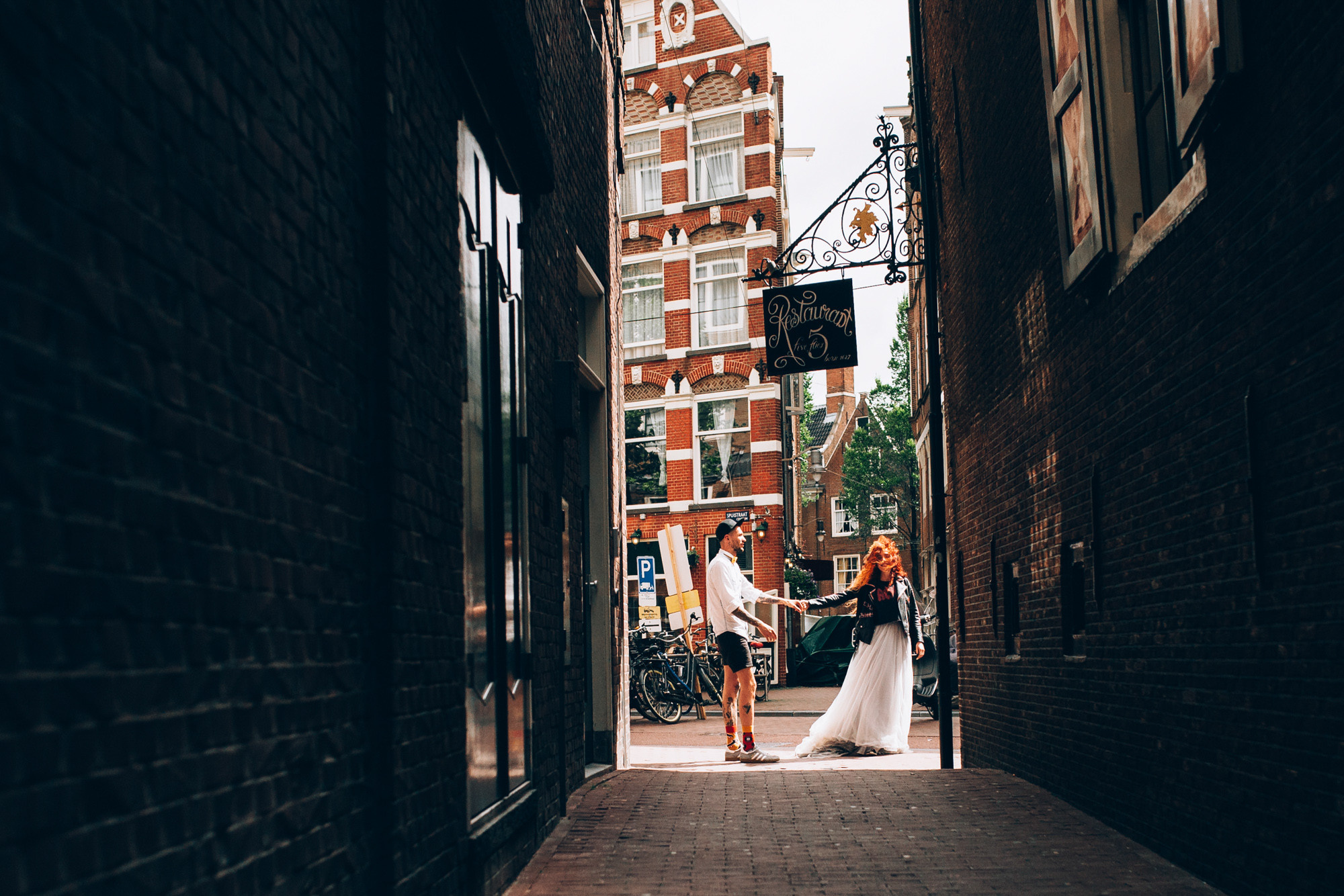 a bride and groom walking down a narrow alley