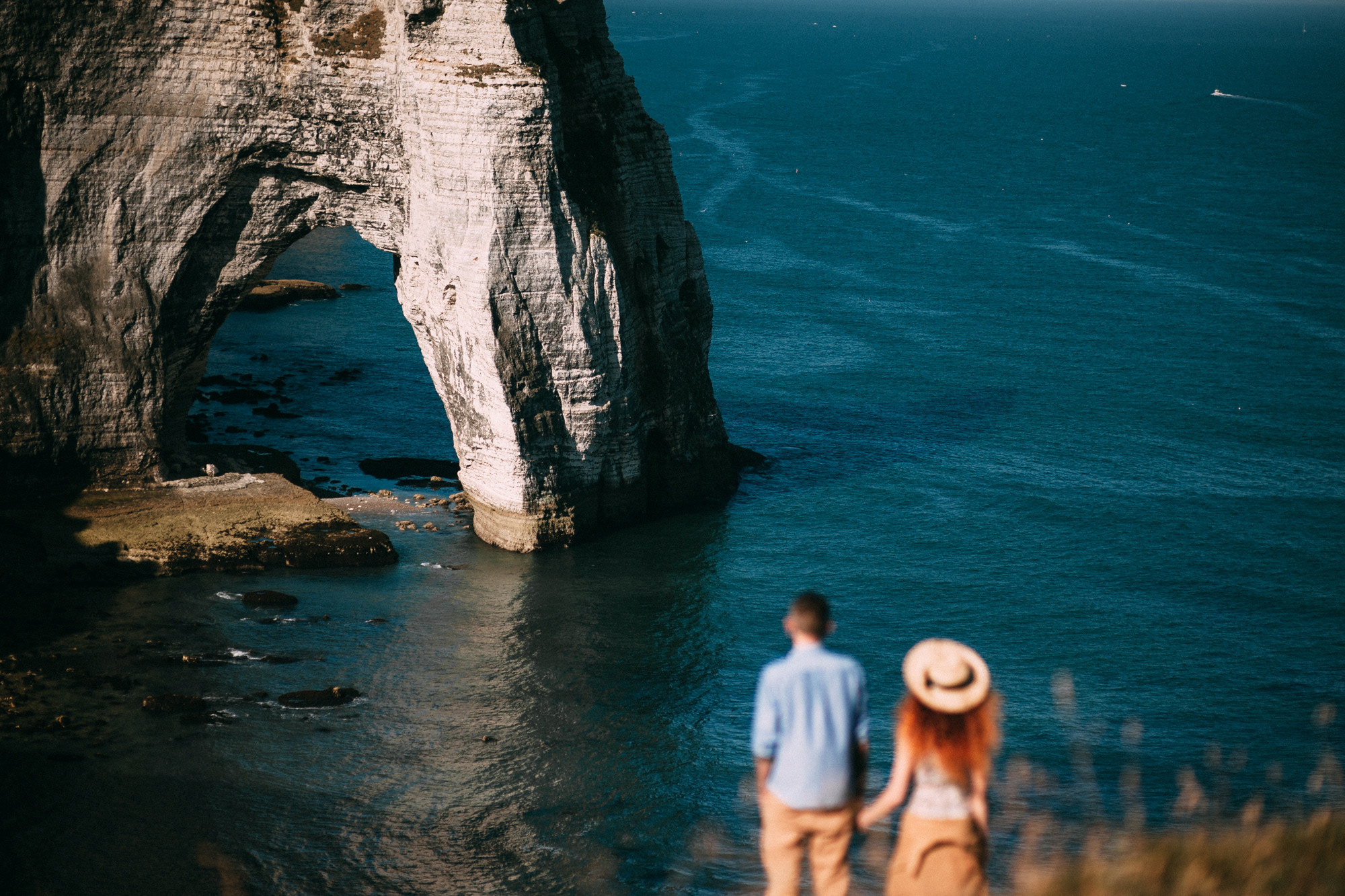 a man and woman standing on a cliff overlooking the ocean