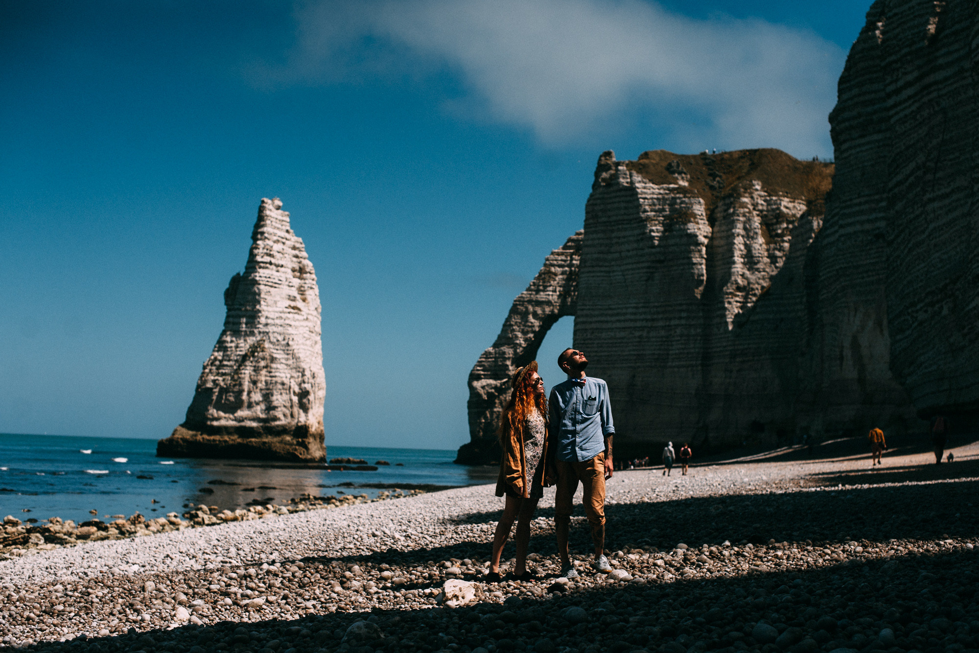 a man walking on a rocky beach next to a rock formation