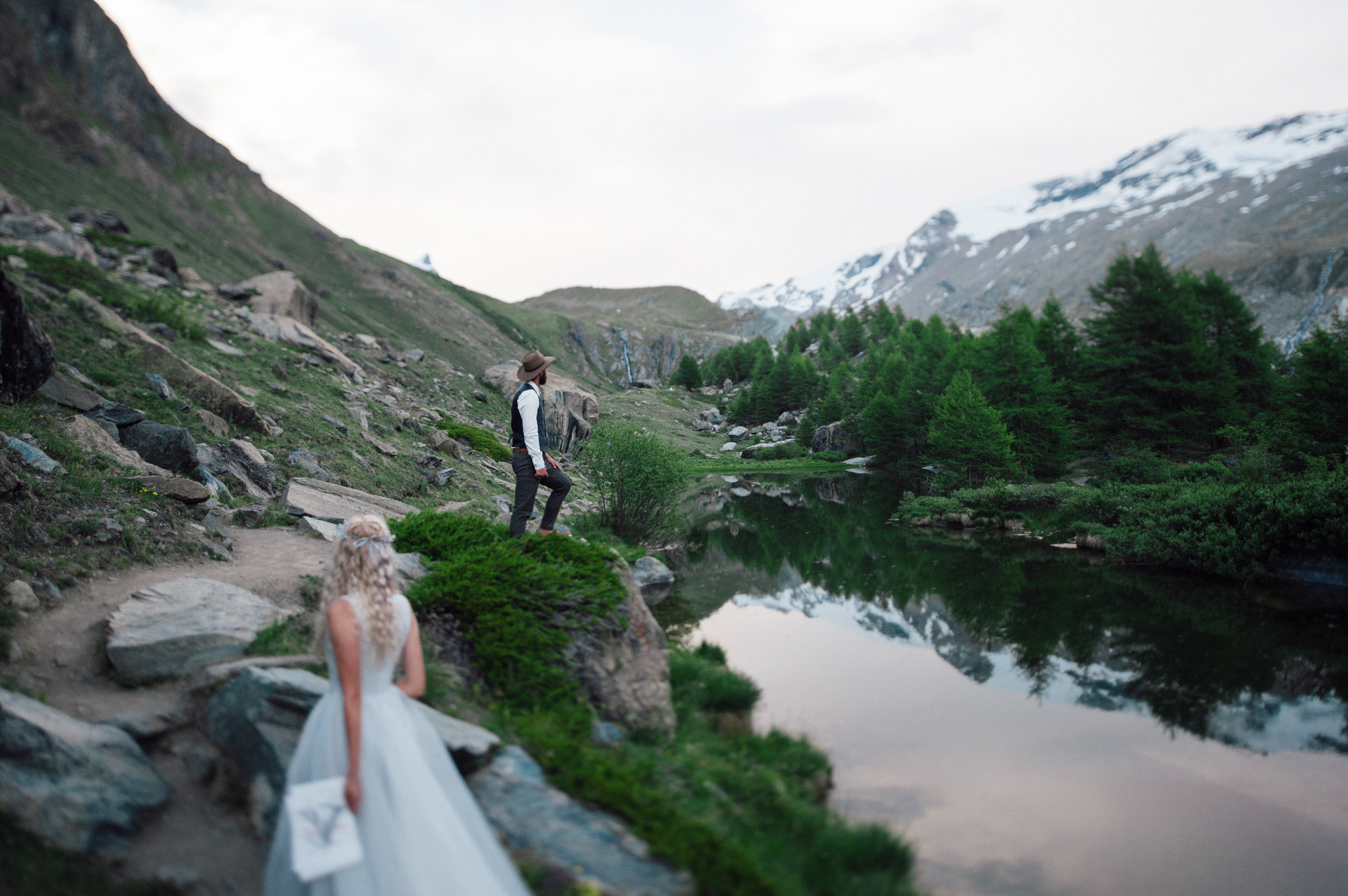 a bride and groom are standing on a rocky mountain