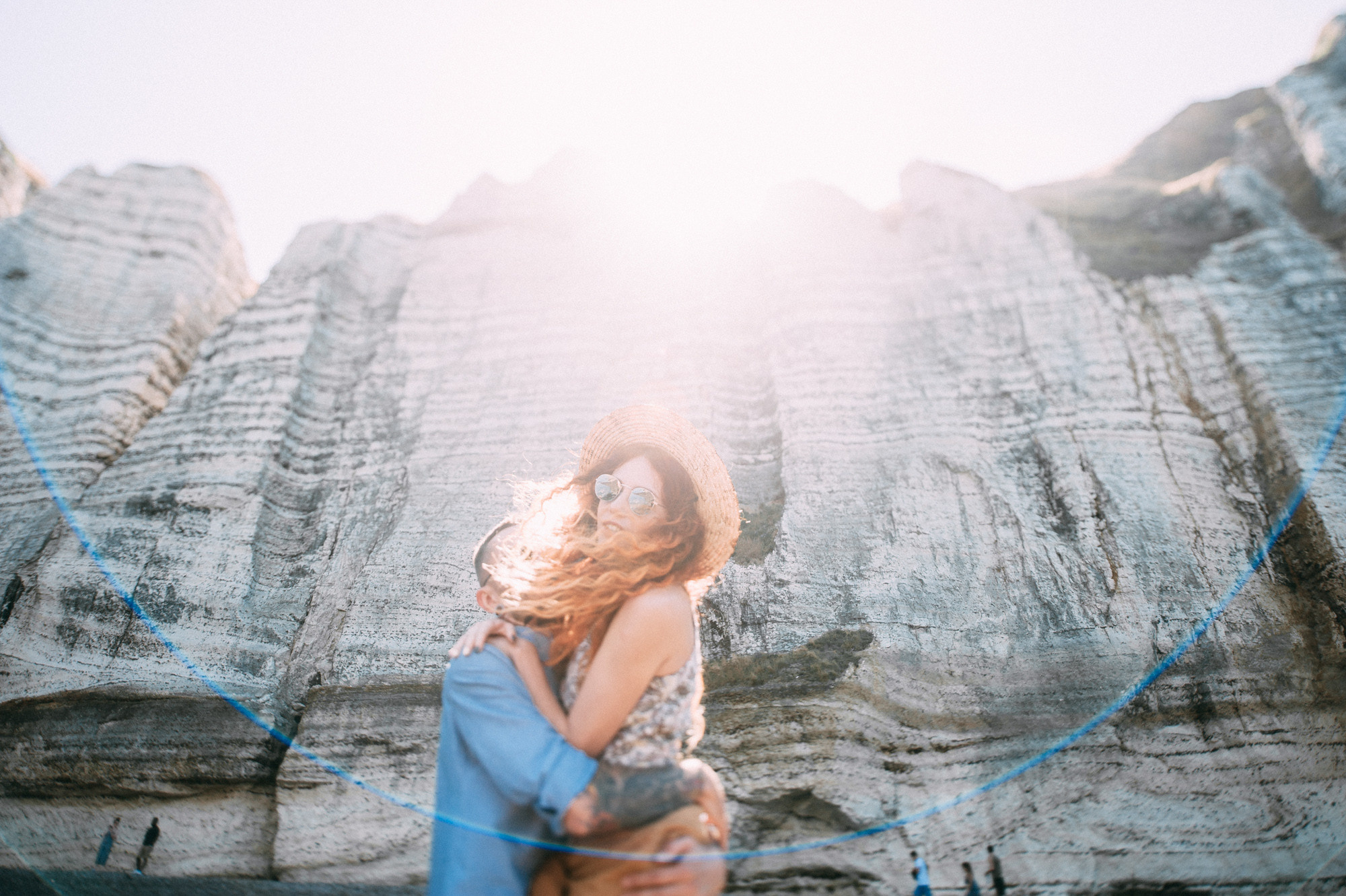 a woman in a blue dress standing in front of a rock