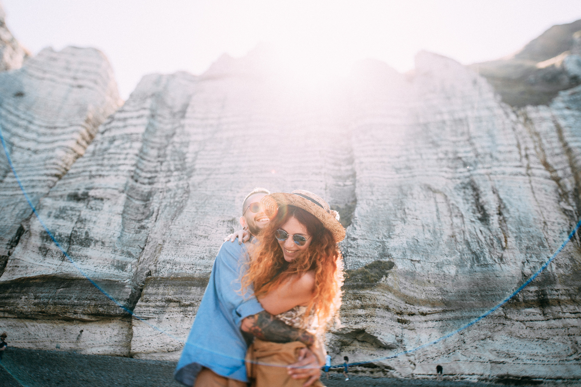 a woman in a blue shirt and hat holding a dog