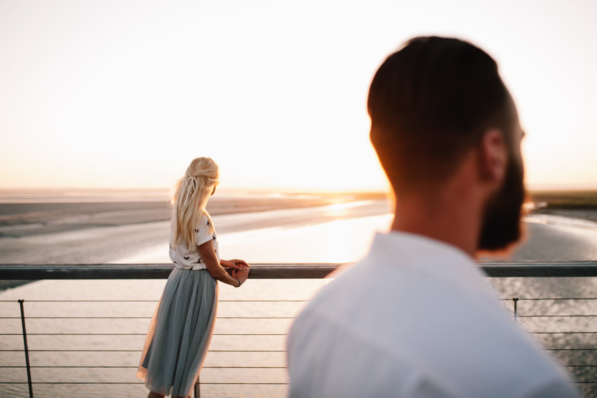 a man and woman standing on a balcony looking at the ocean