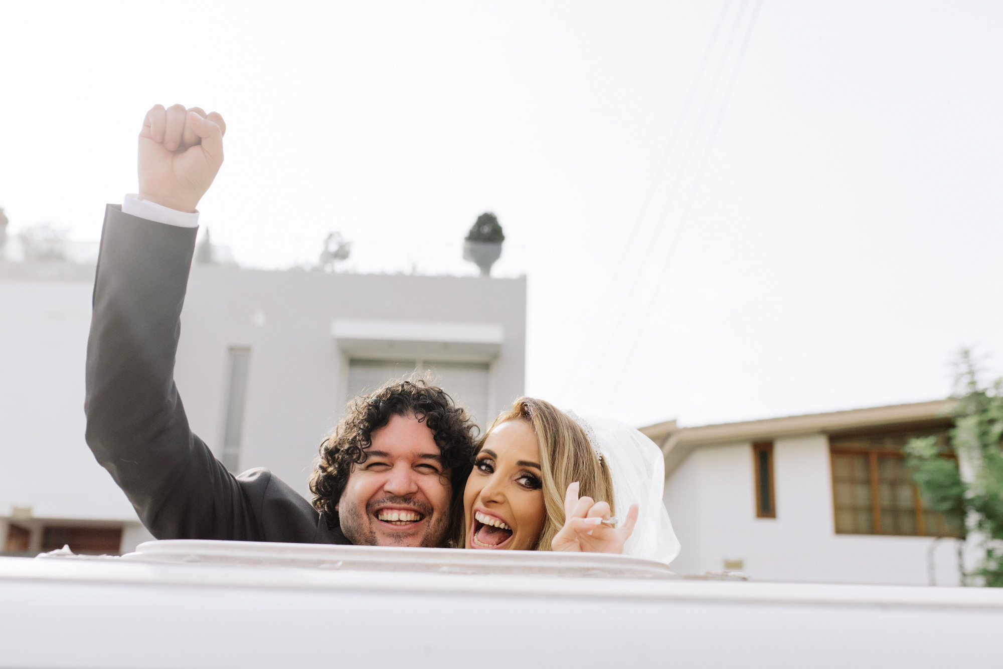 a bride and groom are waving from the back of a car