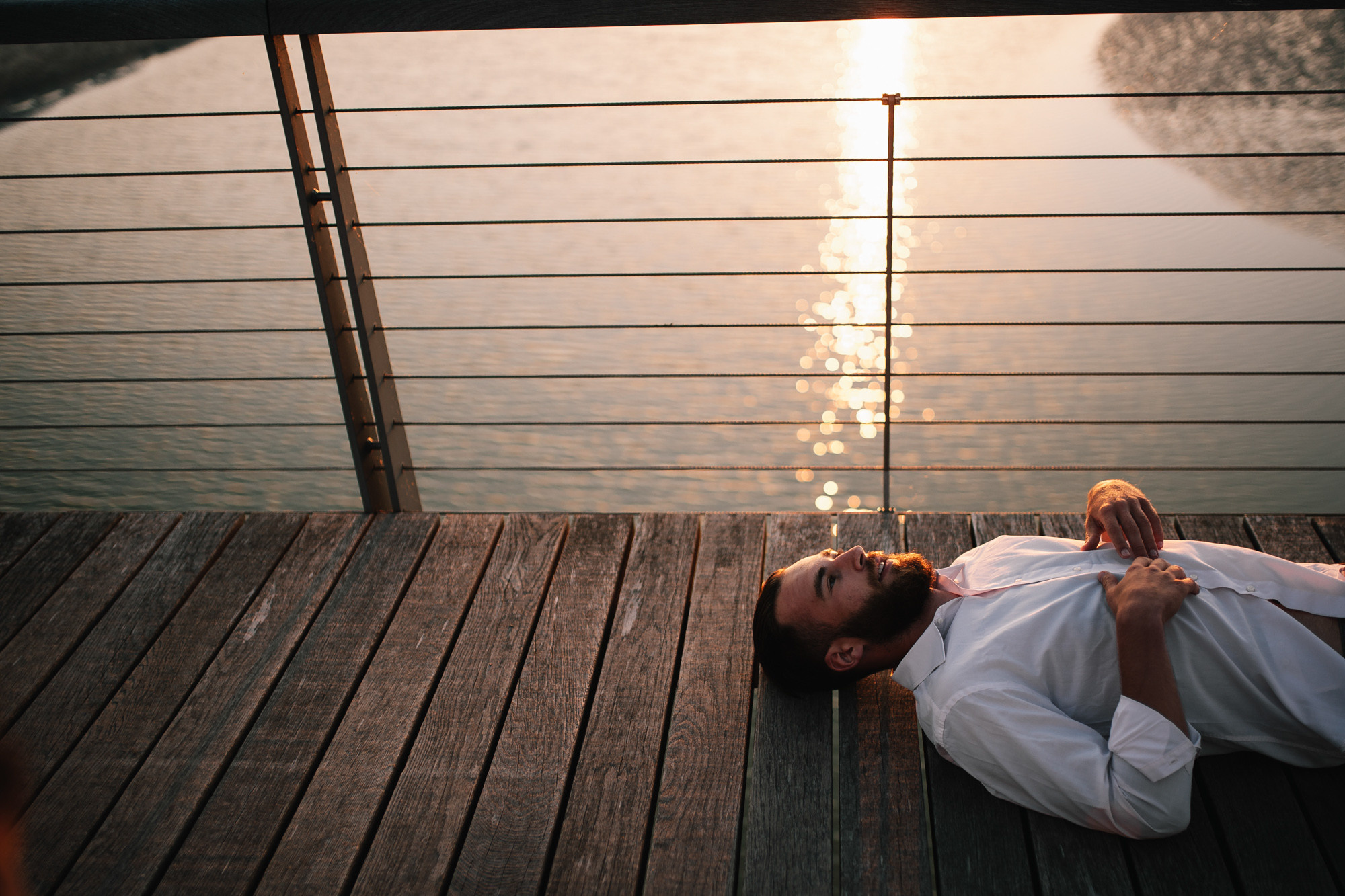 a man laying on a wooden deck next to a body of water